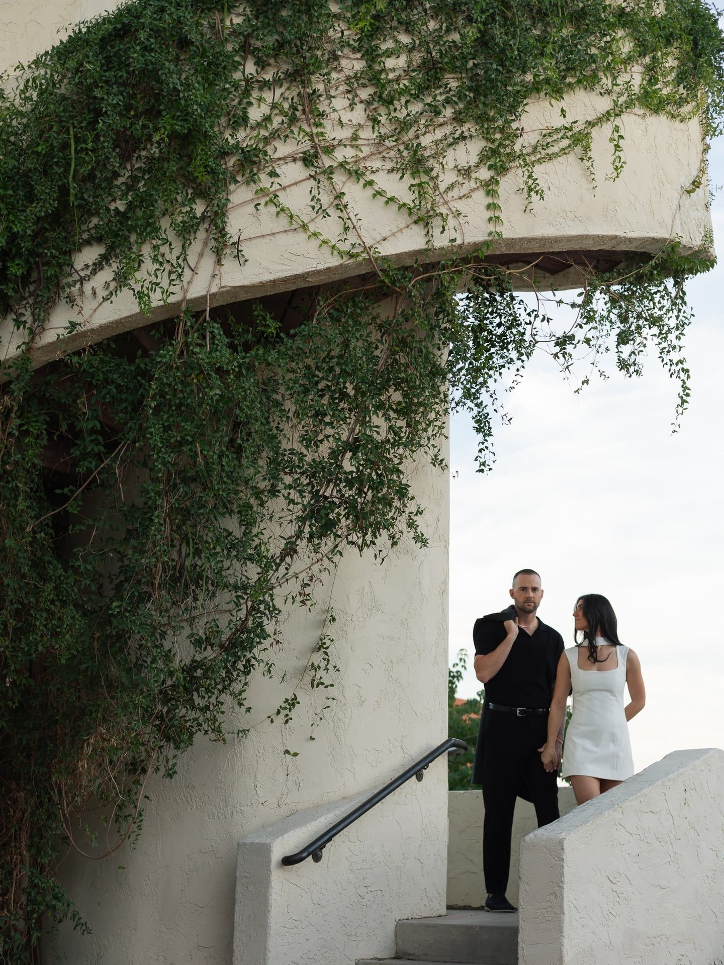 Engagement couple walking together outside ivy covered building capturing natural candid connection