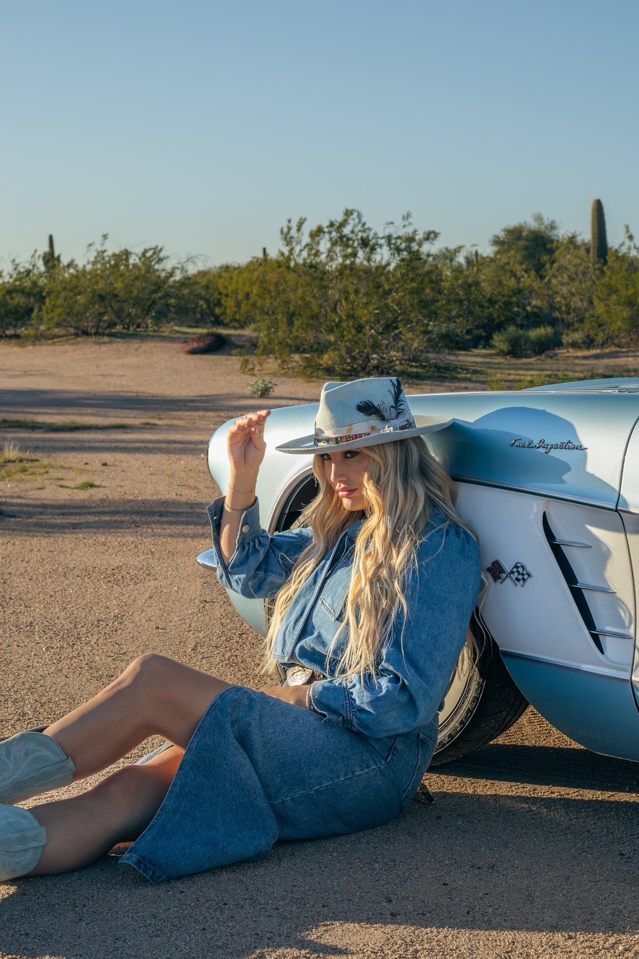 Editorial style outdoor portrait of model with car in Arizona desert with natural golden hour lighting