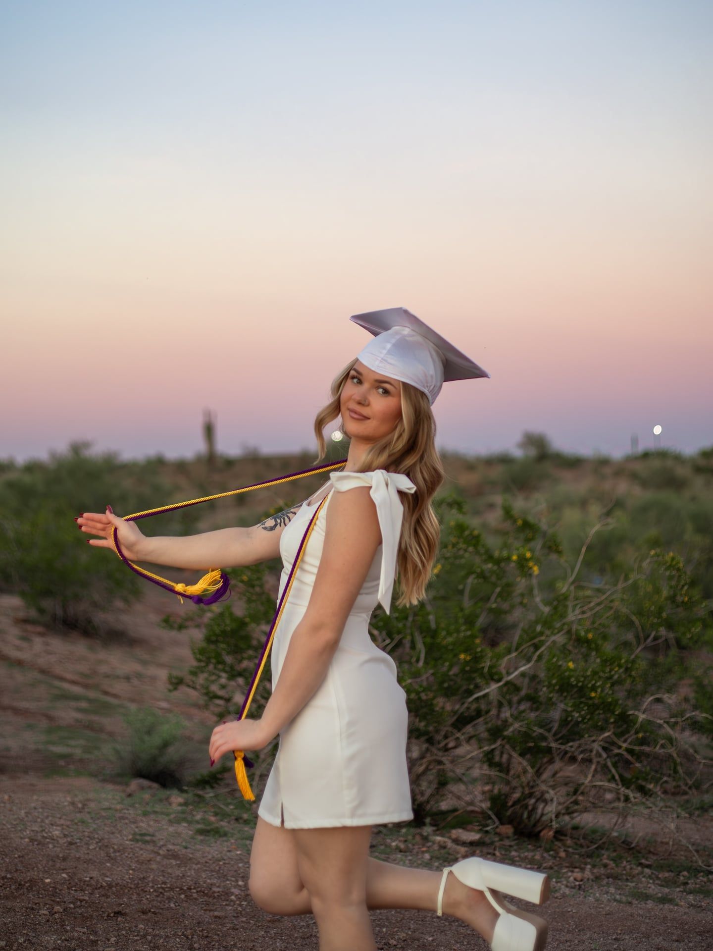 arizona graduate holding tassels during blue hour in the desert