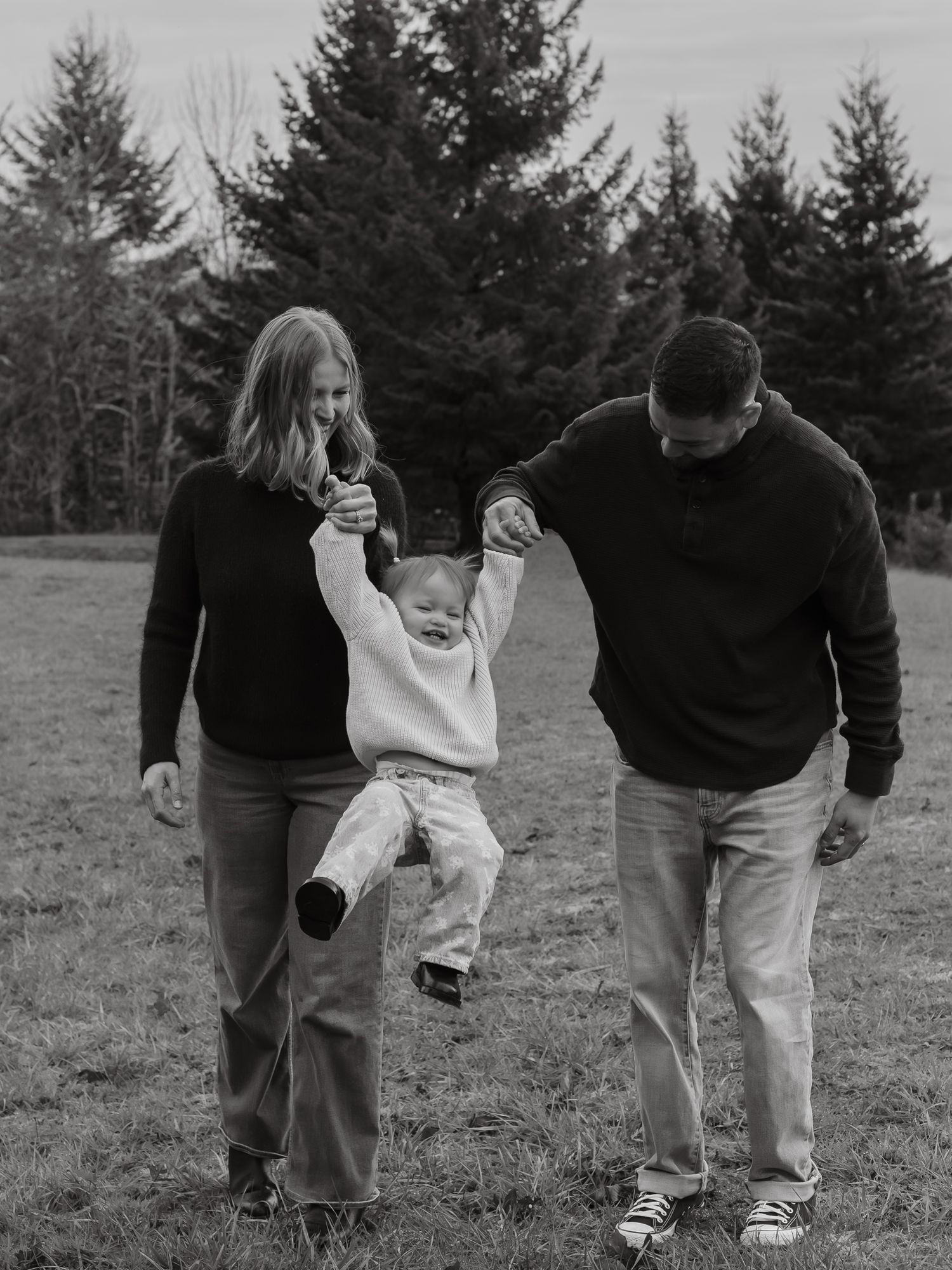 family photo of mom and dad swinging daughter laughing in black and white by kylee gx photography