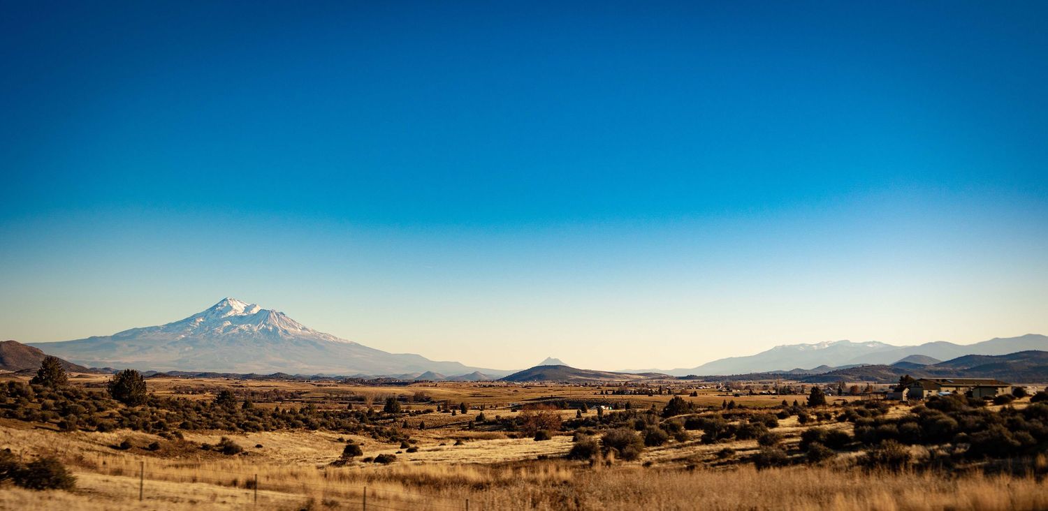 Panoramic desert landscape with mountains and blue sky.