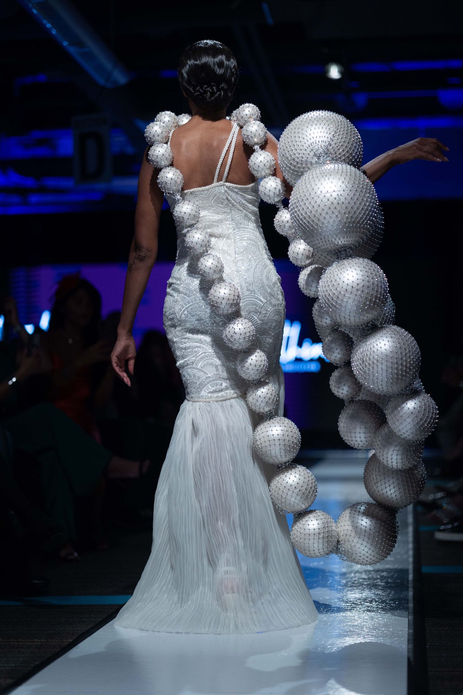 Avant-garde fashion design featuring white dress with silver disco ball spheres.