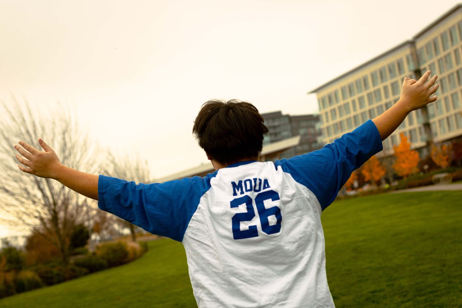 Soccer player wearing a white jersey with number 20 celebrates with arms outstretched on a grass field.