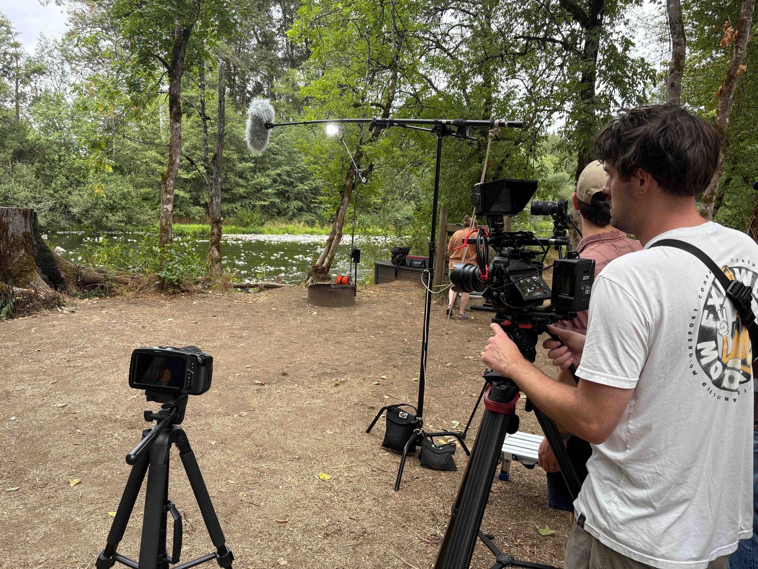 Film crew with professional camera equipment set up to shoot in a wooded outdoor location.