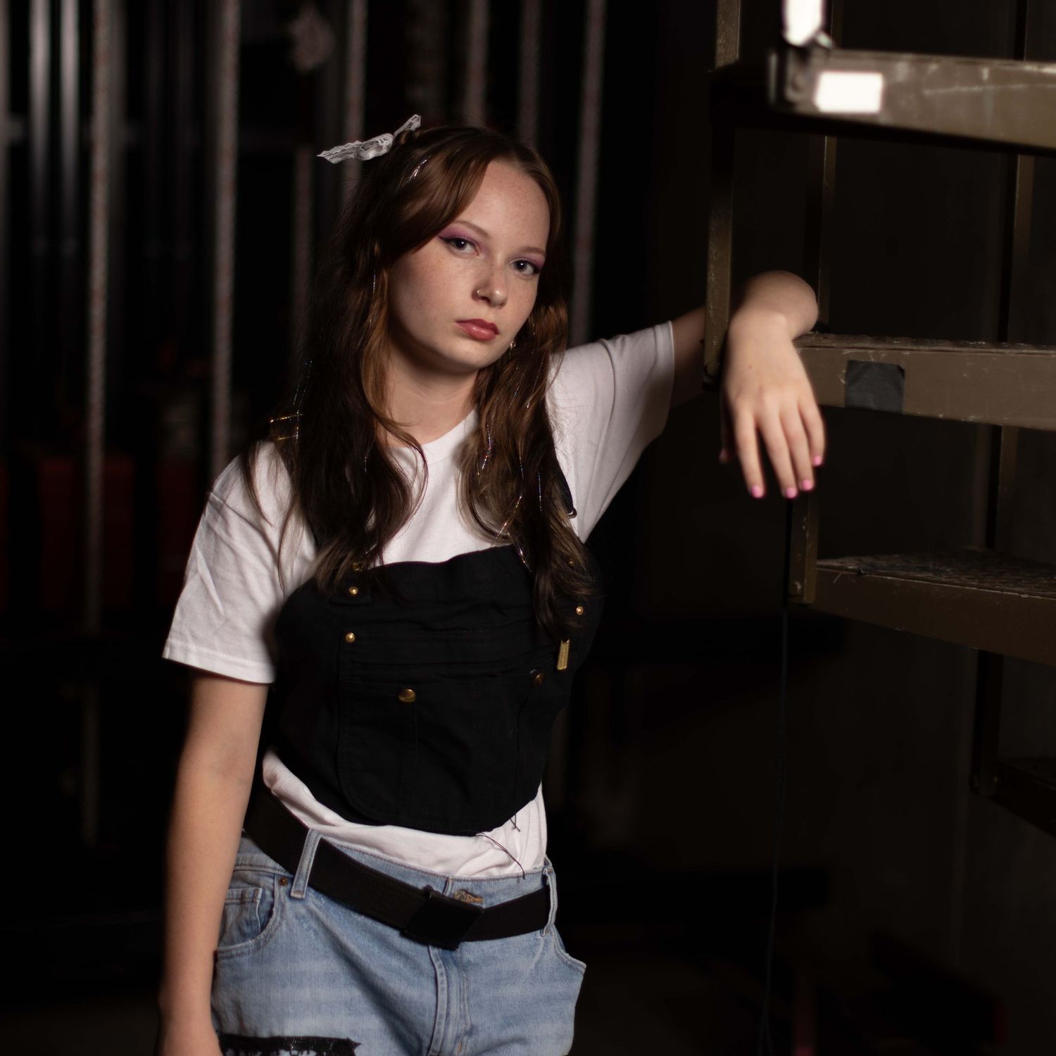 Person in white t-shirt and jeans poses against dark background in fashion photoshoot series.