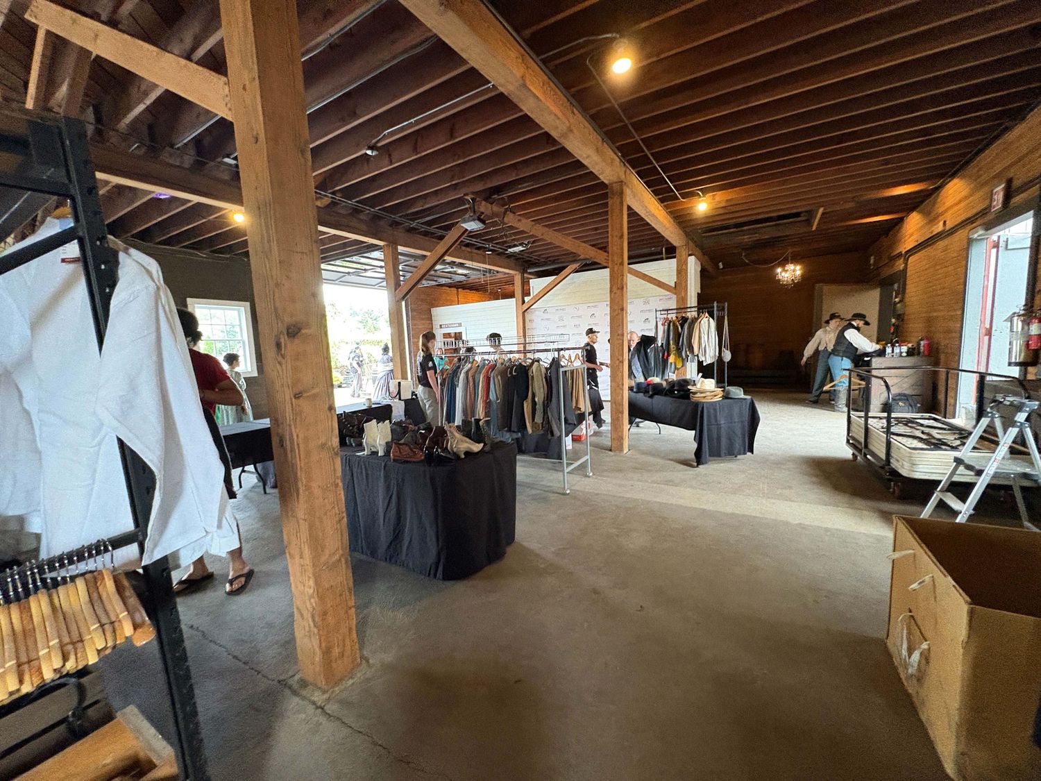 Interior view of a clothing retail store with exposed wooden beams, racks of garments, and warm lighting.