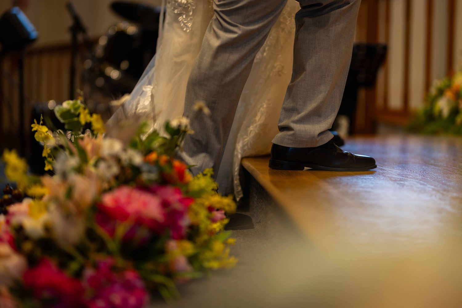 Colorful floral arrangements line a wooden table in an indoor setting with natural lighting.