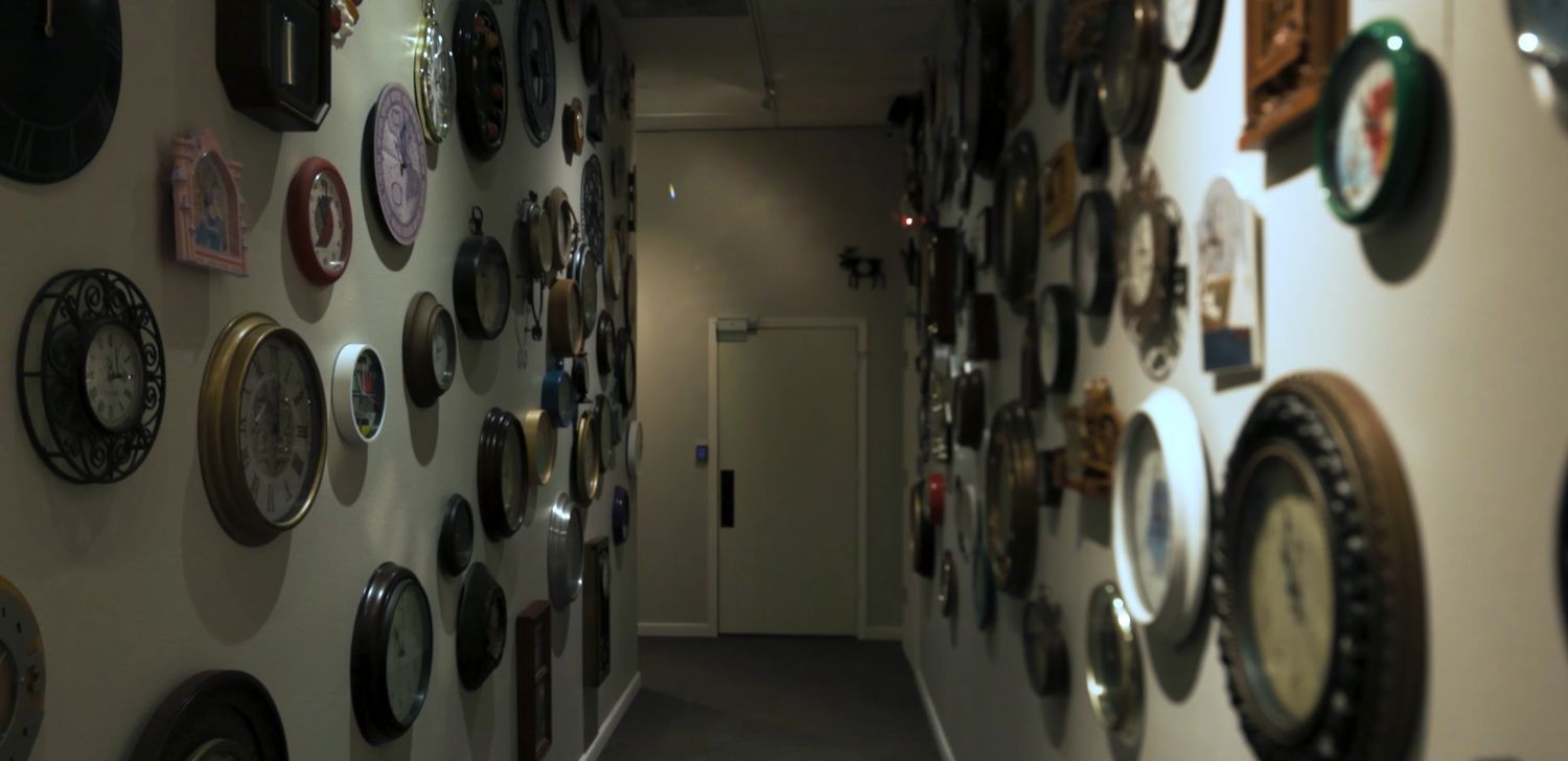 A wall decorated with numerous vintage clocks and timepieces in an antique store display.