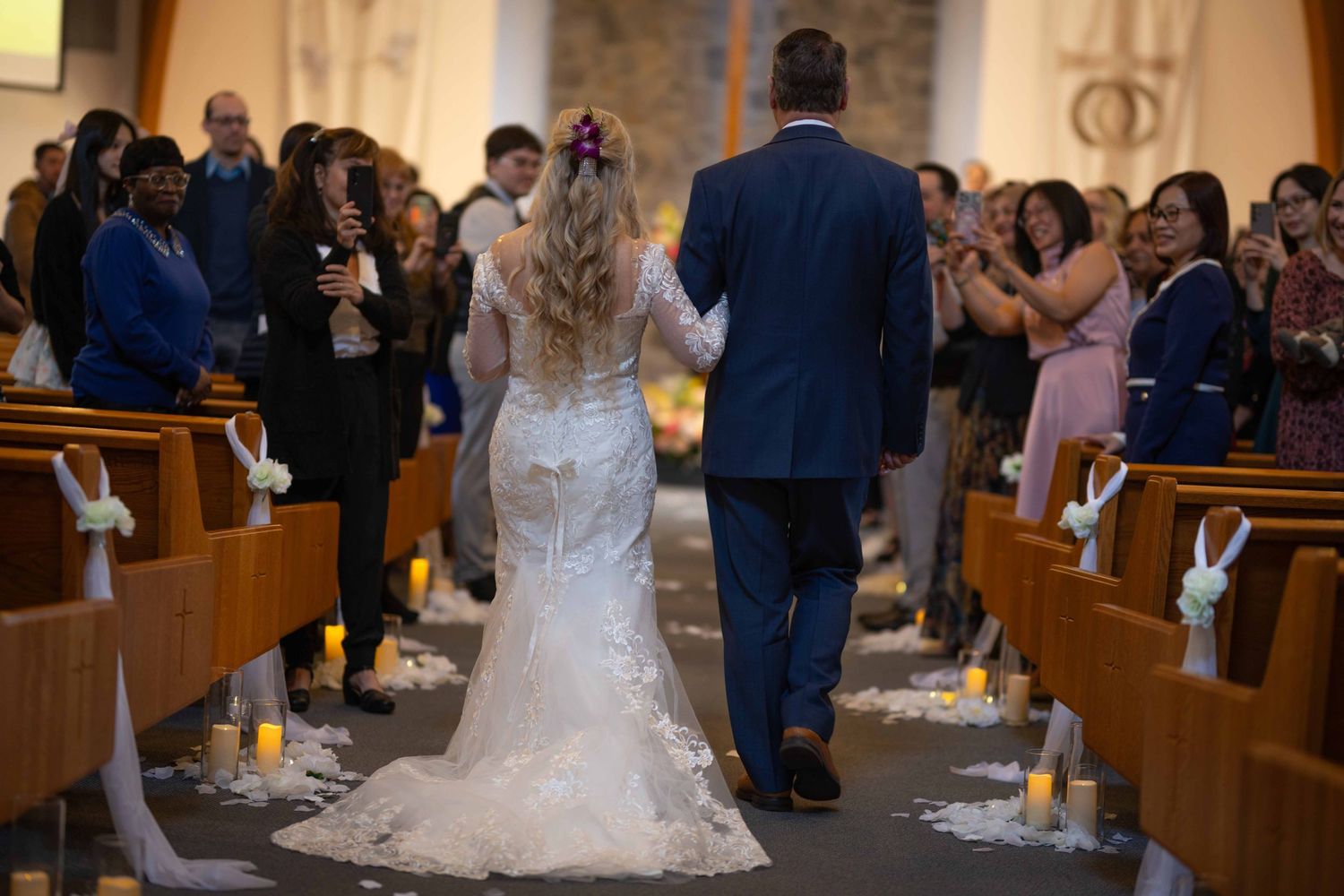 Wedding ceremony attendees gather in wooden church pews during a traditional indoor ceremony.