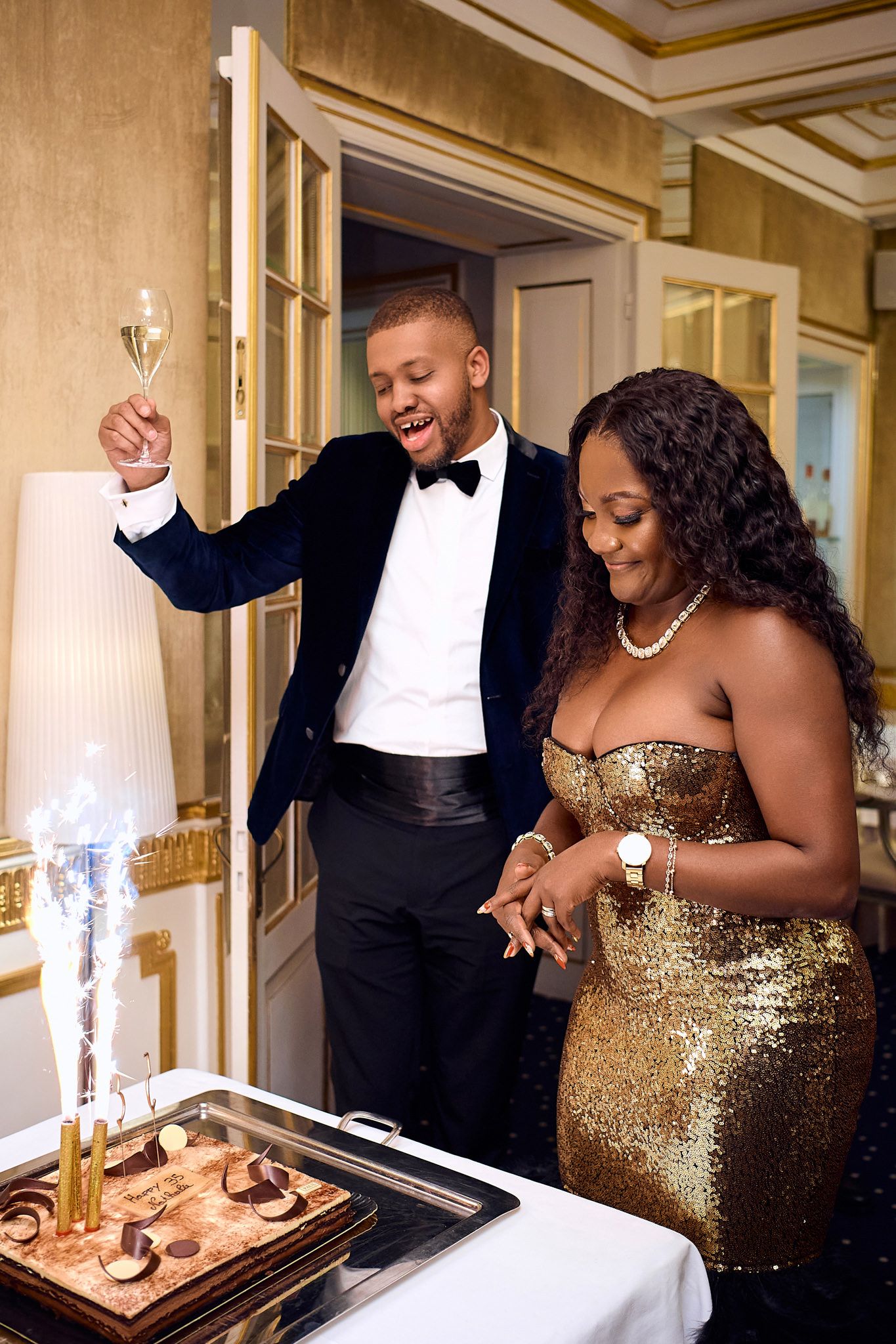 Couple in formal attire shares playful moment while cutting cake at elegant reception.