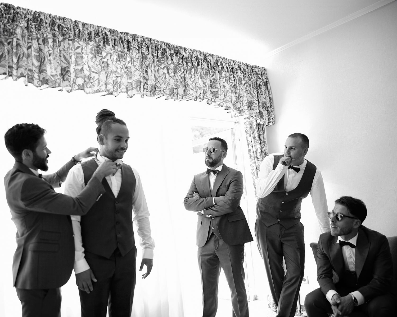 Stylish groomsmen in suits posing in creative black and white silhouette formation.
