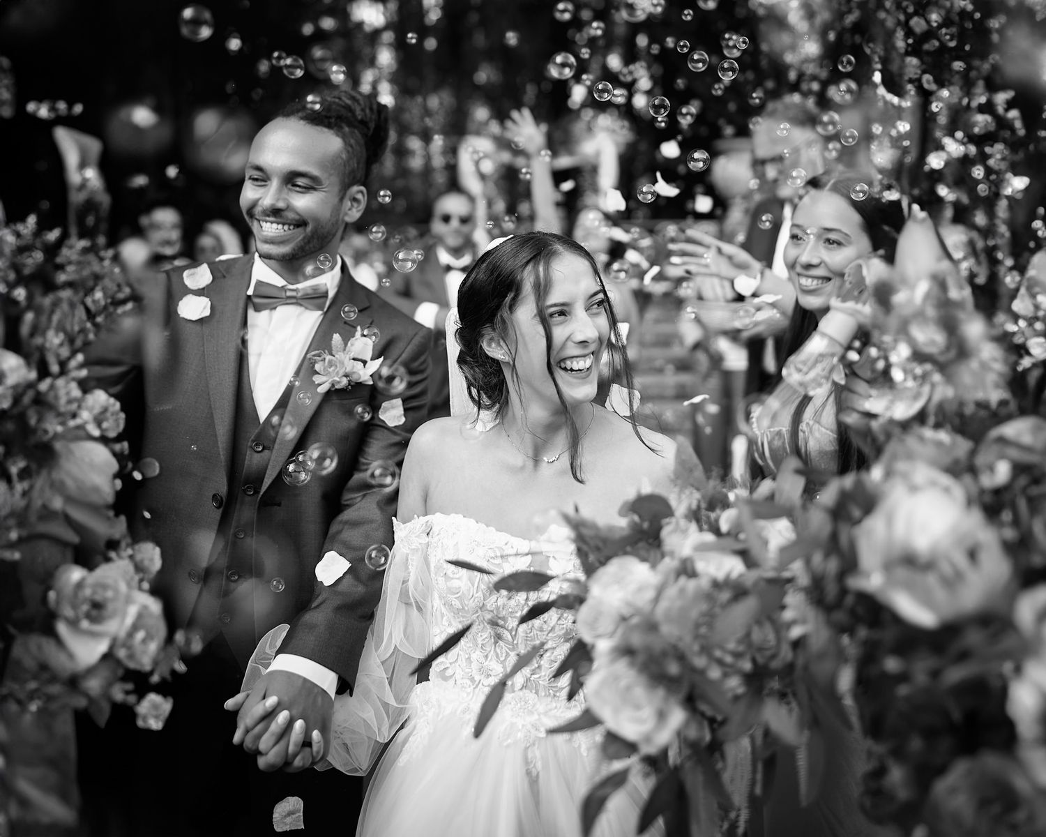 Wedding guests celebrate with bubbles and laughter during an outdoor celebration.