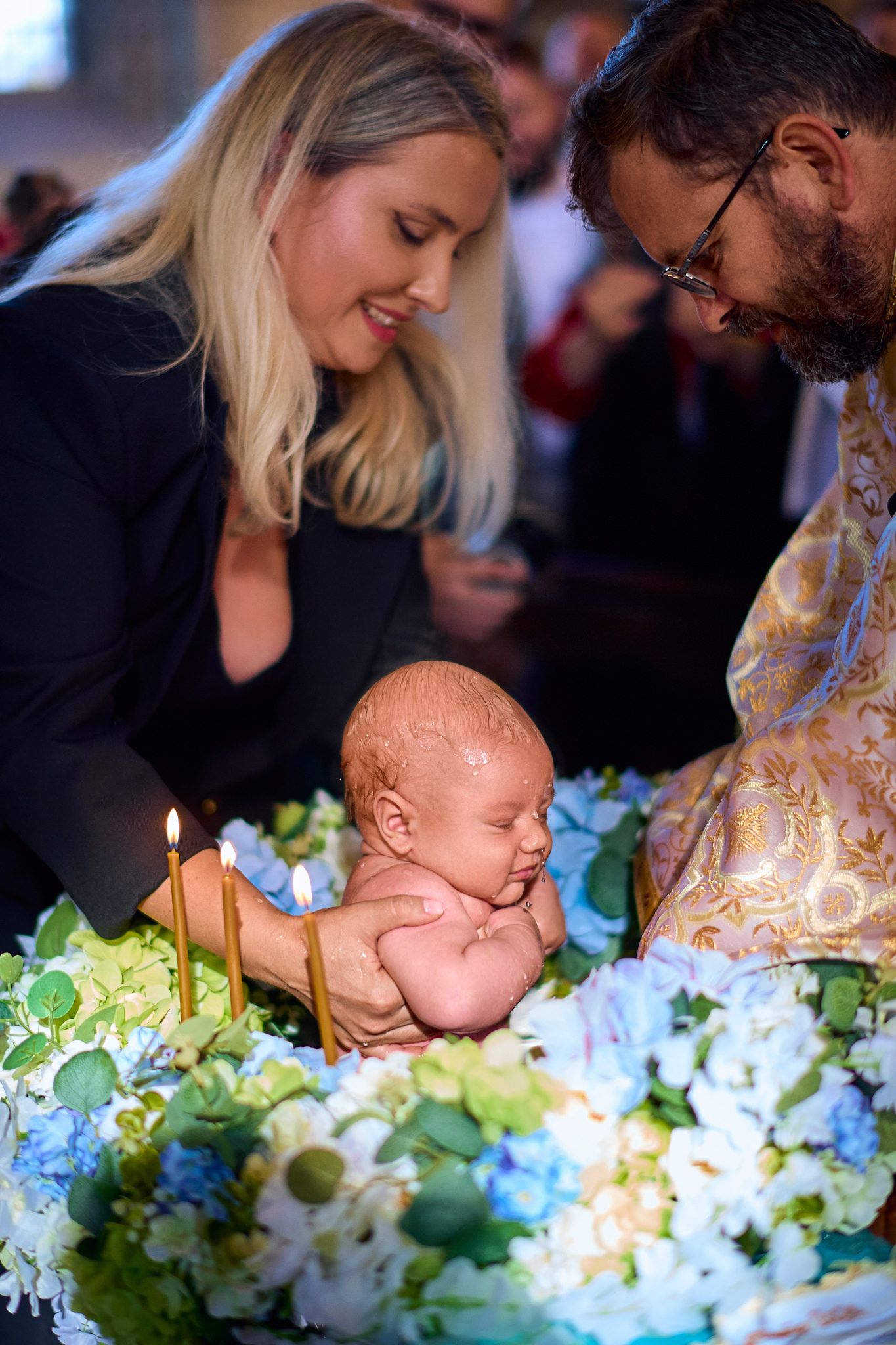 Baby rests on floral arrangement with blue and white flowers.