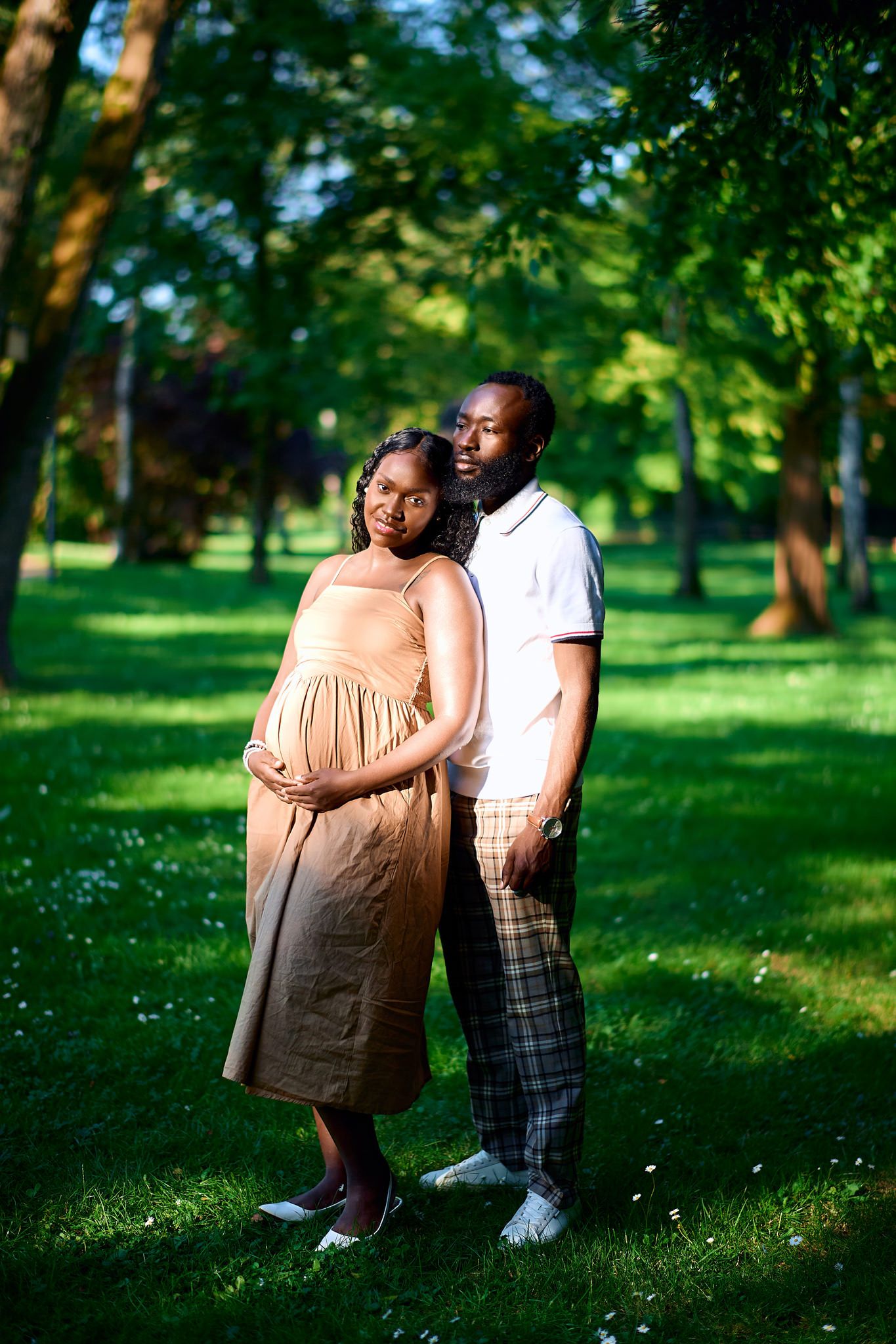 Intimate maternity photoshoot in a lush green park setting.