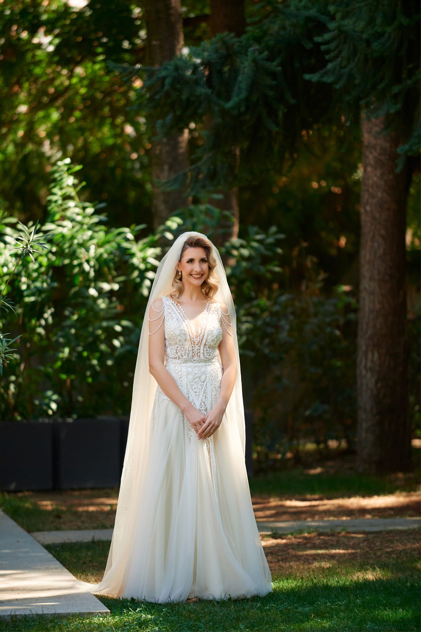 A beautiful wedding dress photographed in a sunlit outdoor garden setting.