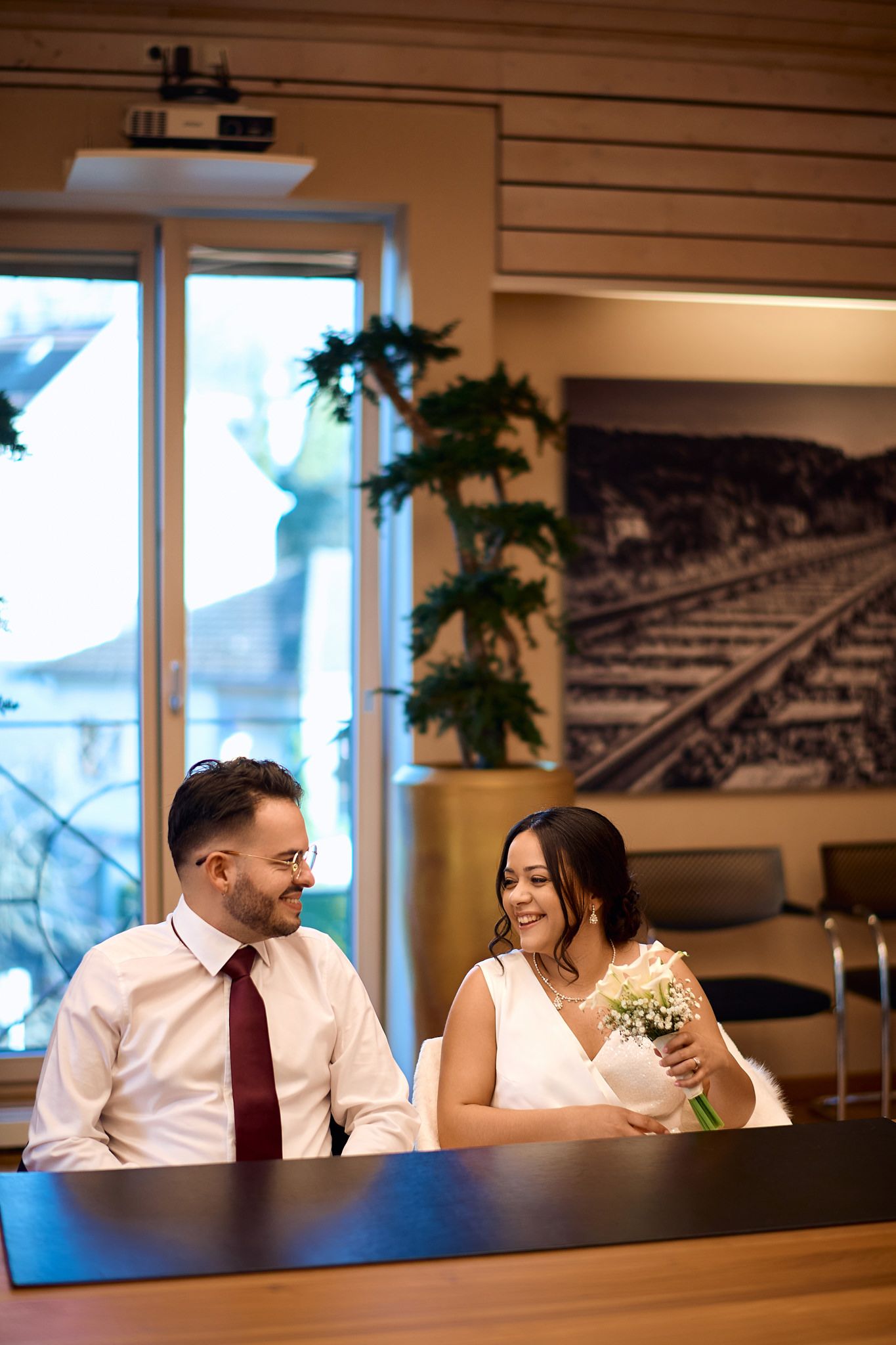 Candid wedding moments captured at a modern venue with industrial-style decor and large windows.