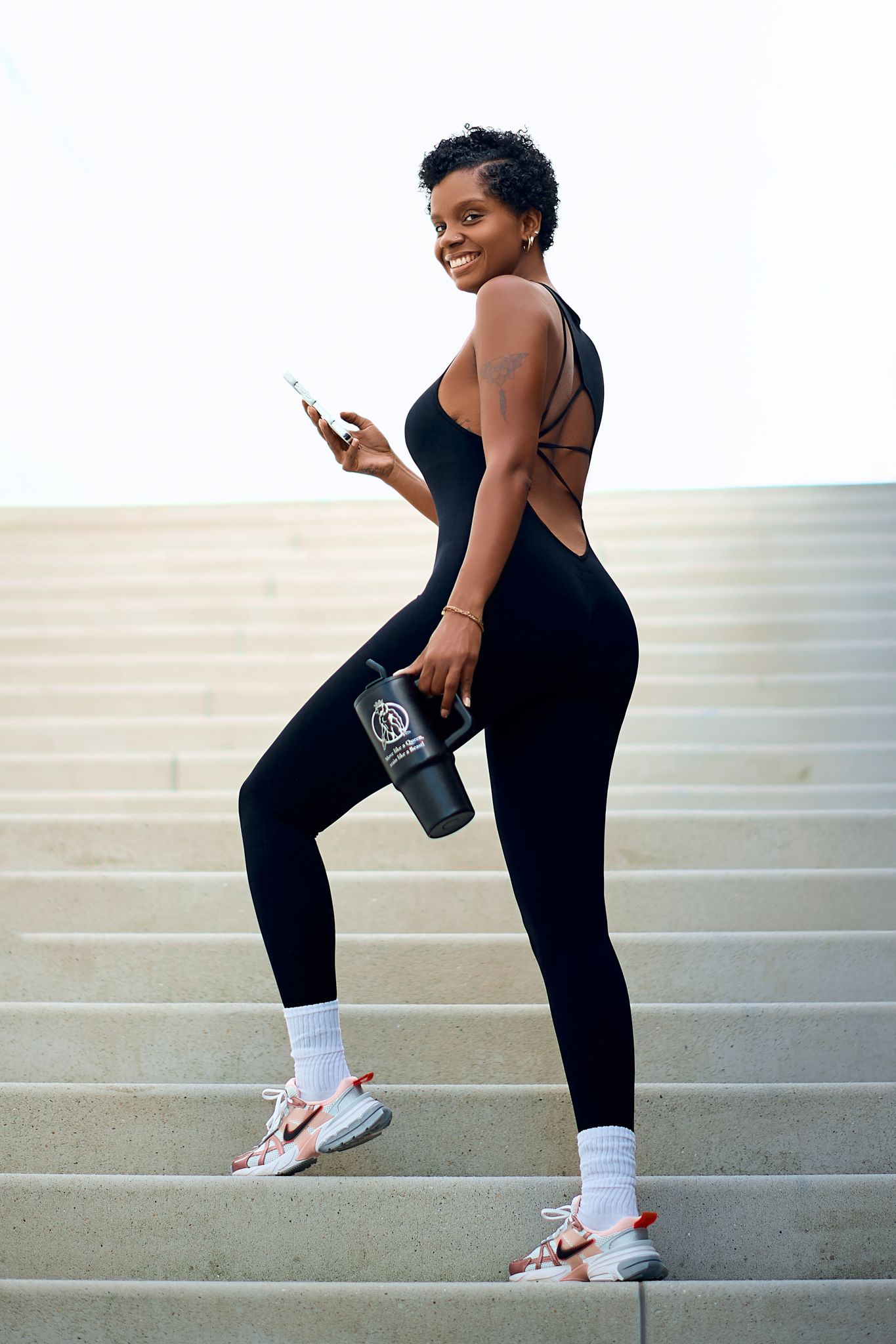 Person in black athletic wear and white socks stretches on outdoor steps during exercise session.