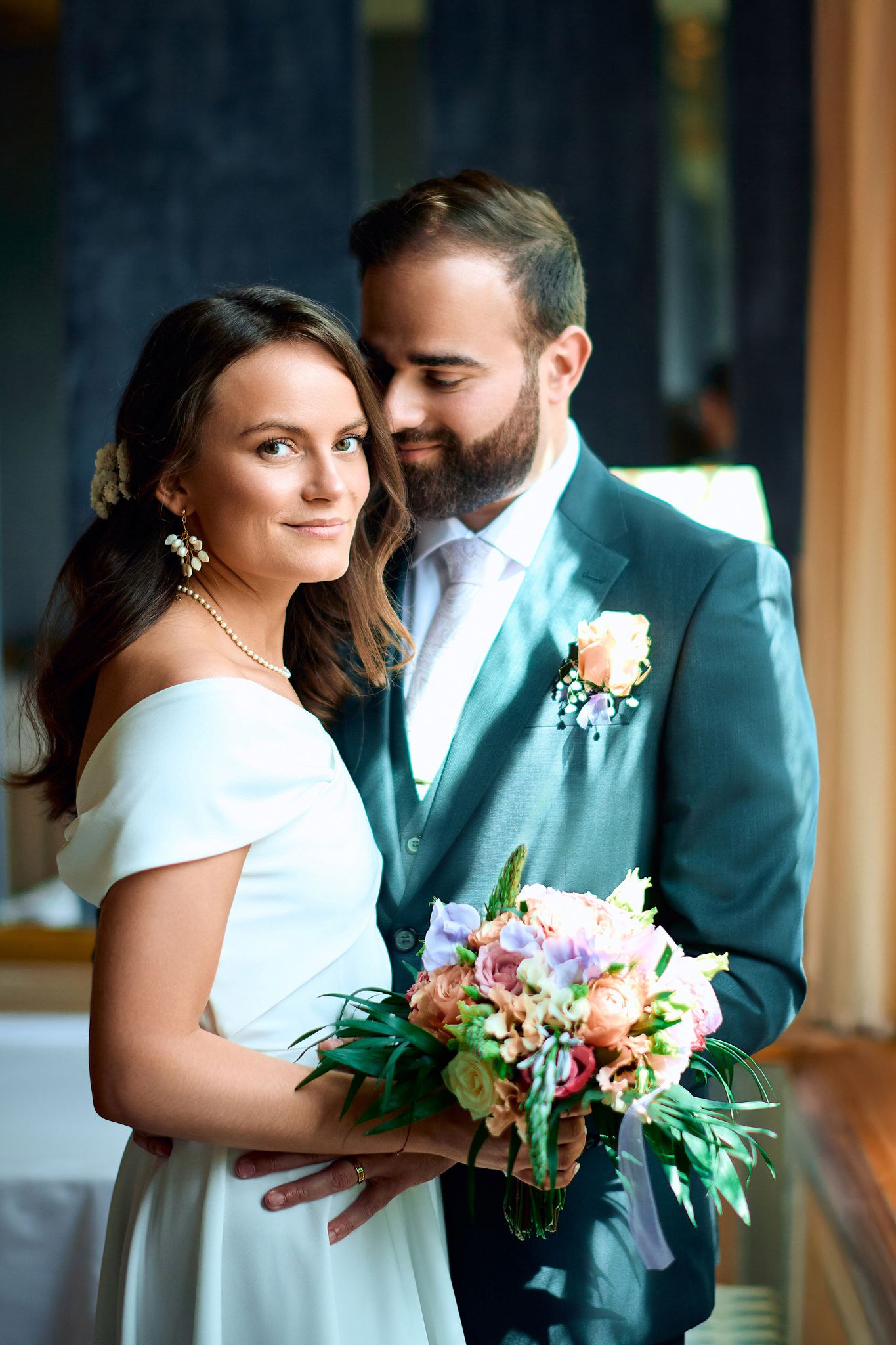 A tender moment shared between a couple in mint green and white wedding attire with florals.