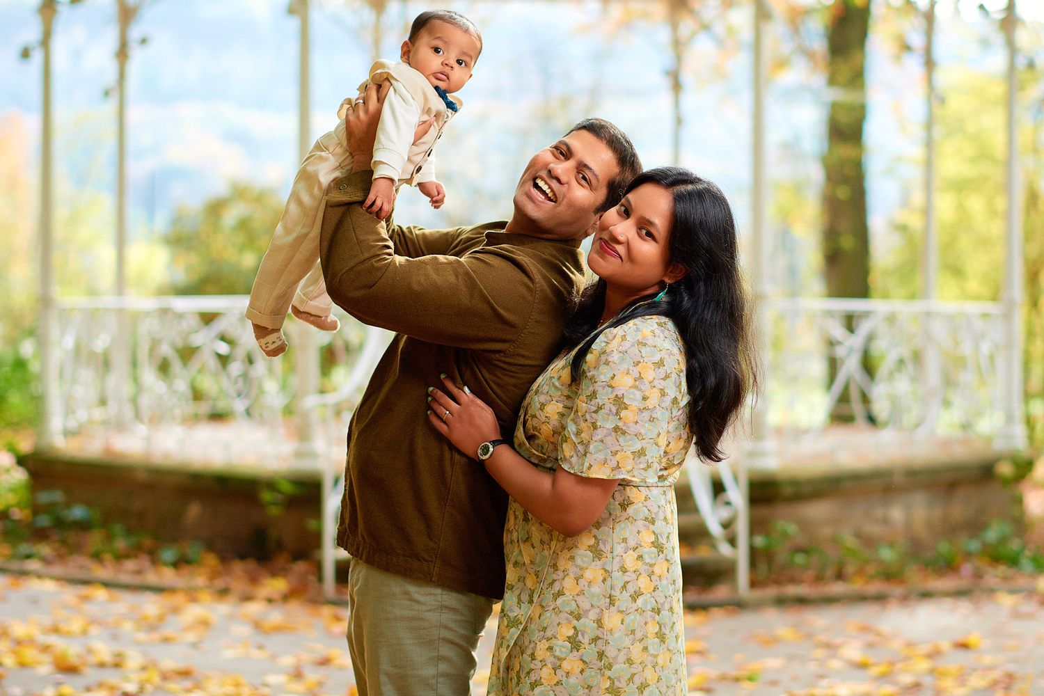 Joyful outdoor family photoshoot with playful poses against autumn foliage.
