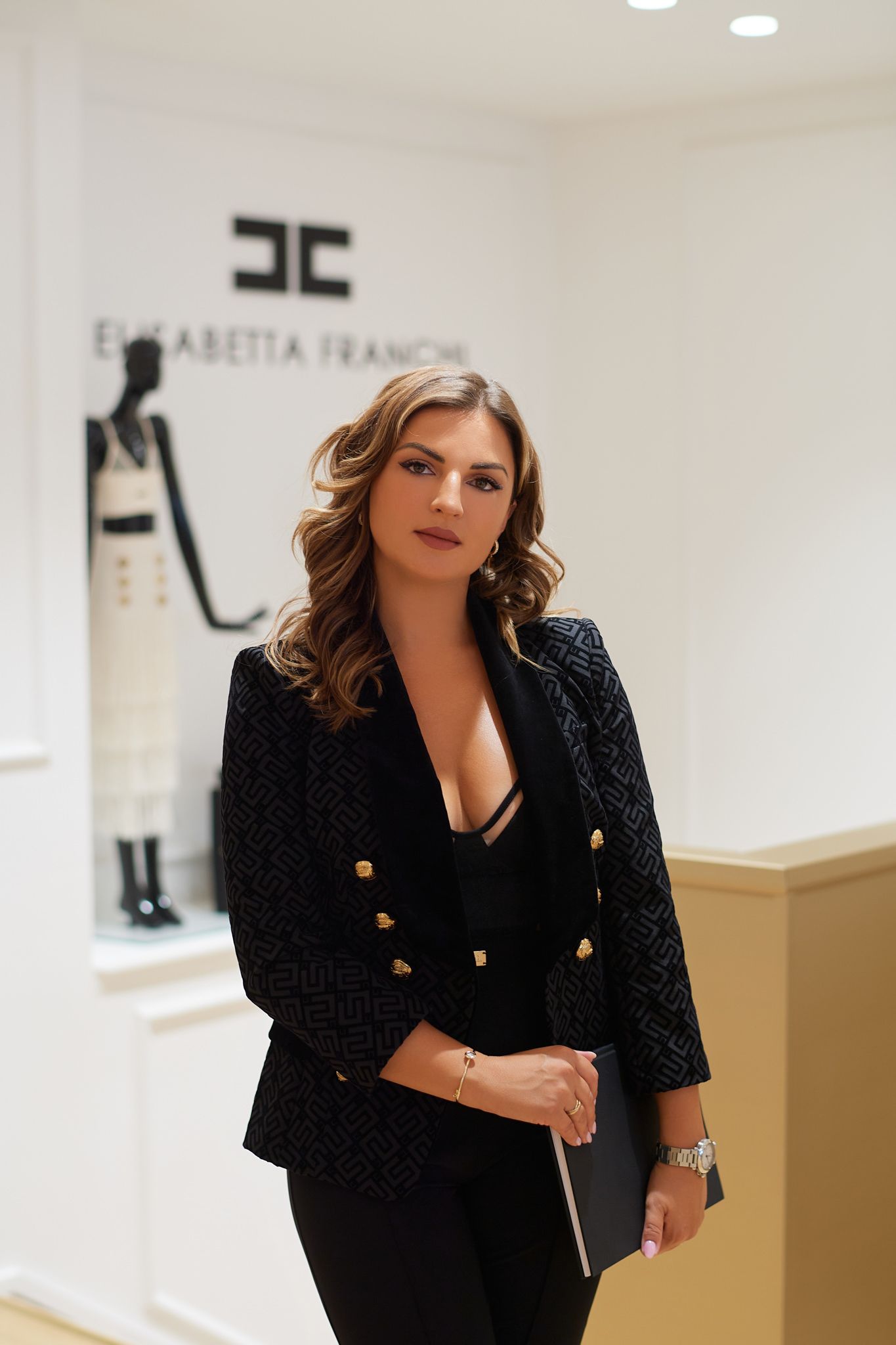 Business professional in dark blazer poses confidently in upscale retail environment.