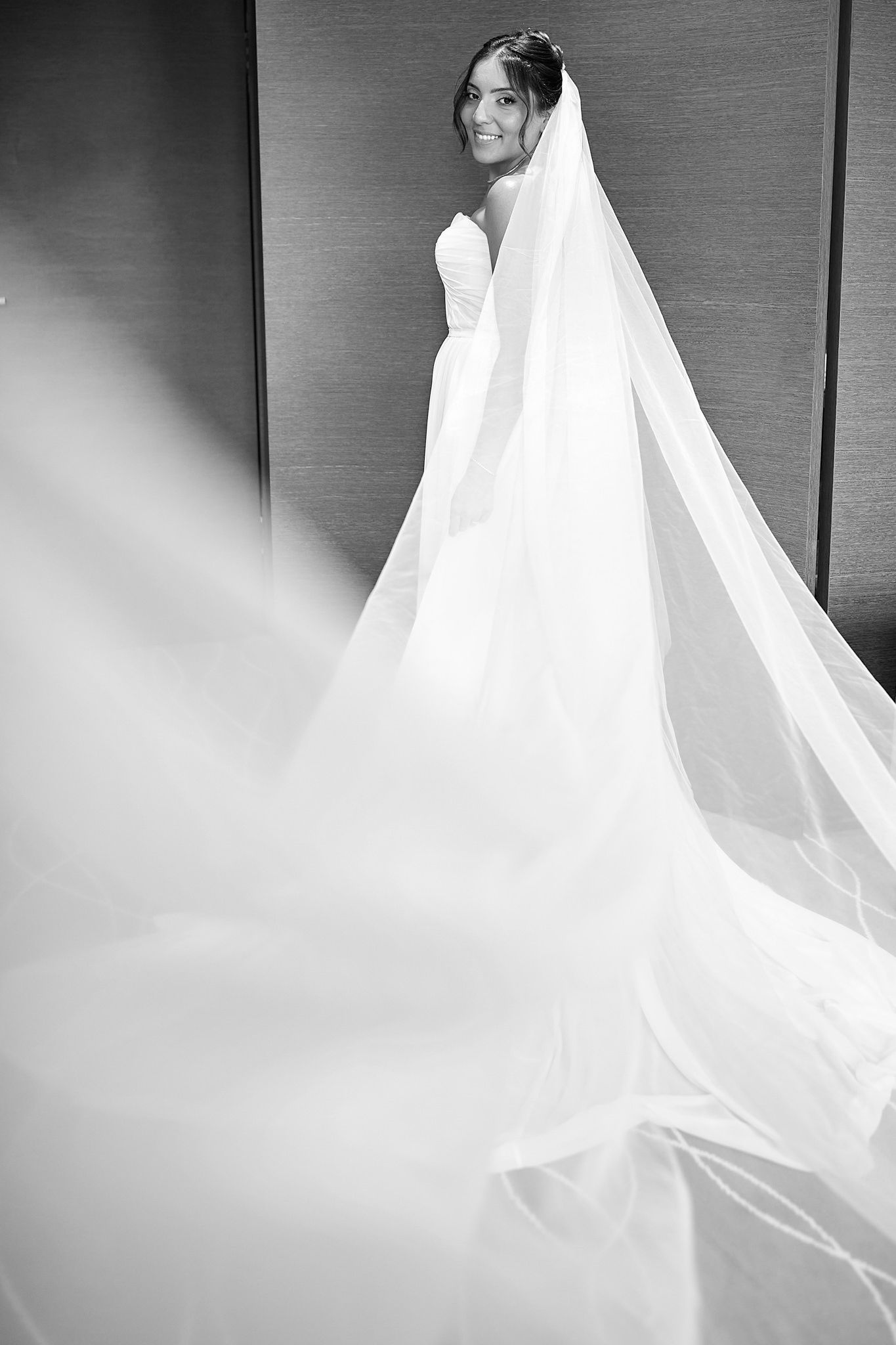 Dramatic black and white portrait of a bride with flowing cathedral veil.