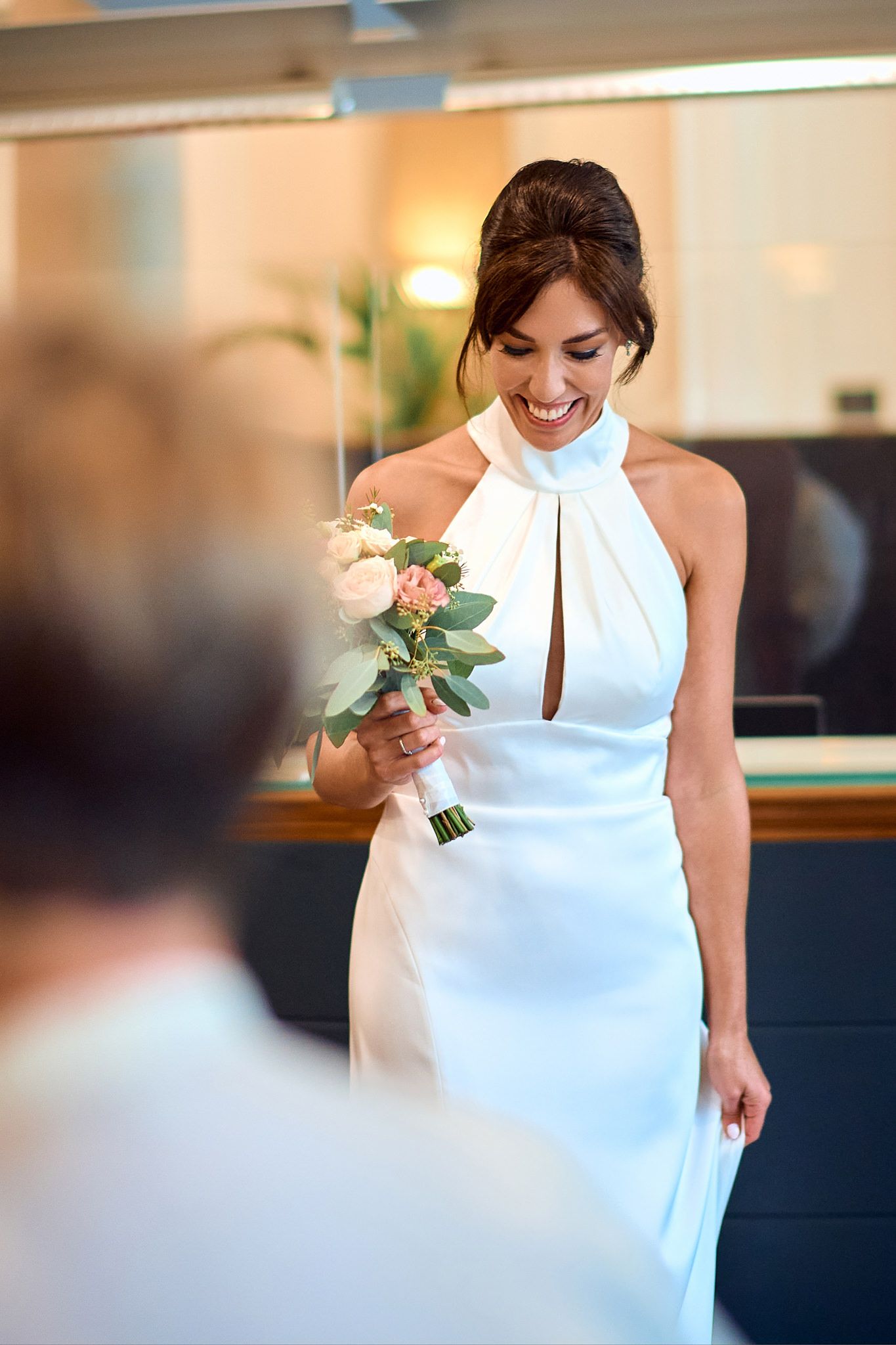 A bride in an elegant white dress walks gracefully through an indoor space.
