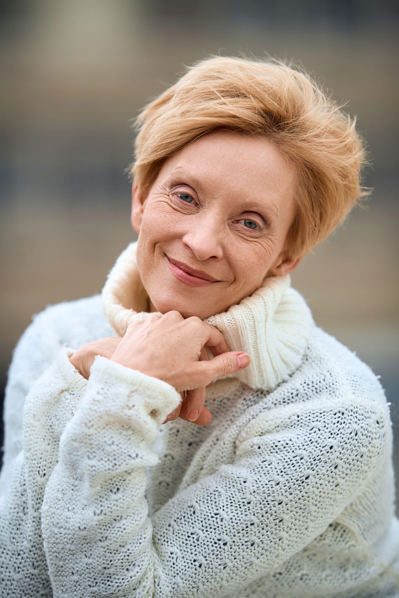 Person in white knit sweater showing playful expressions against dark background.