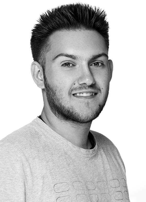 Professional headshot portrait of a young man in a gray t-shirt against white background.