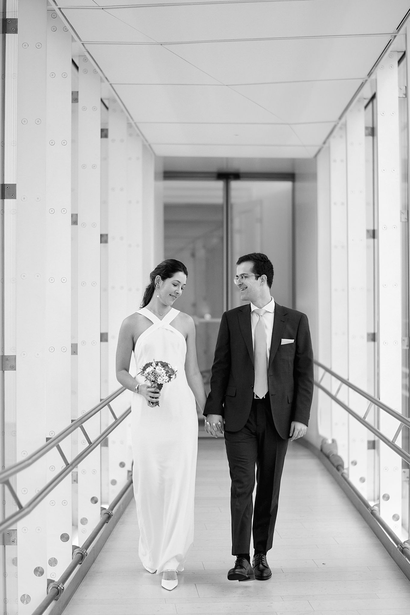 Black and white wedding photos in modern hallway with minimalist architecture.