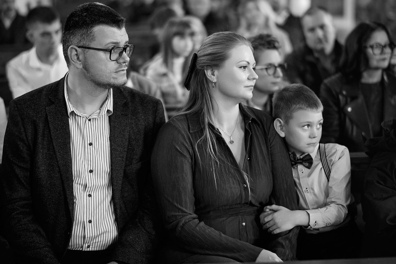 Audience members watch intently during formal event in auditorium.