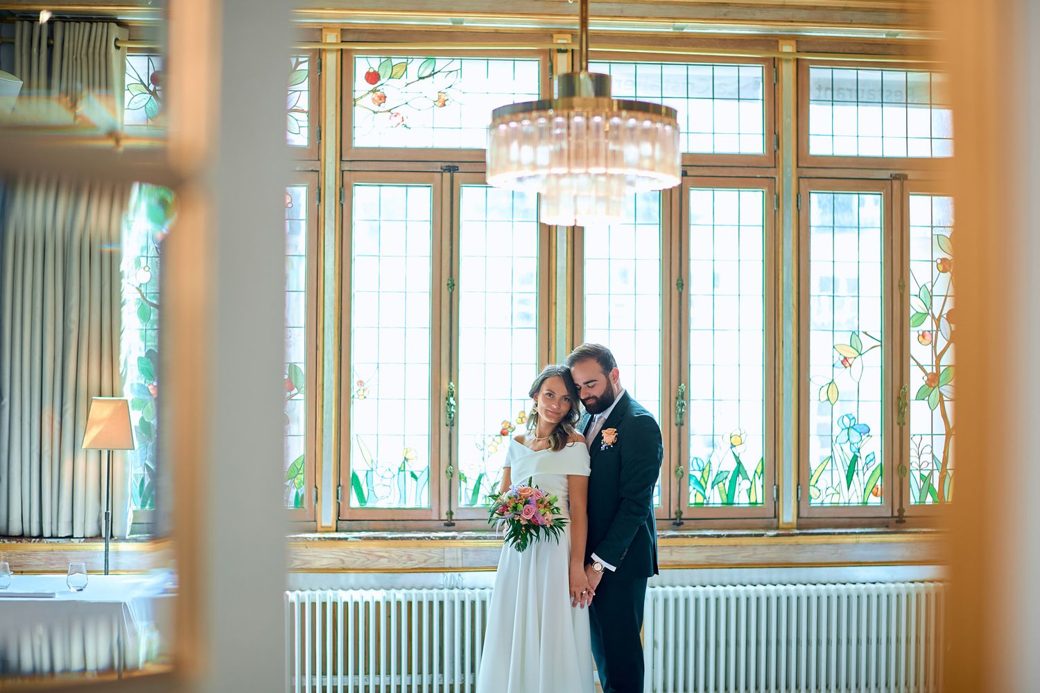 An intimate wedding moment captured in a bright, window-lit indoor venue.