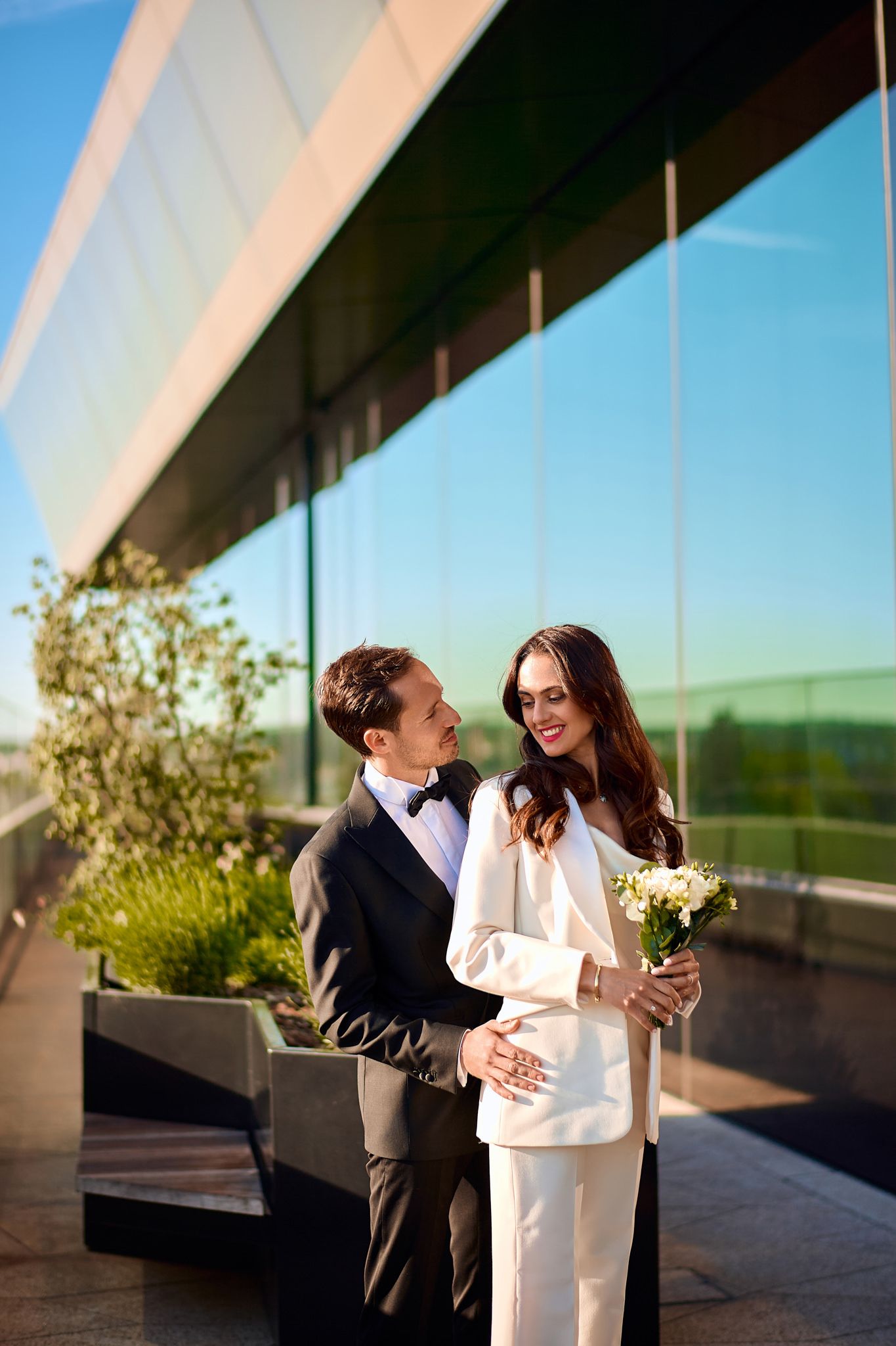 Couple shares romantic moment on modern building terrace at sunset.