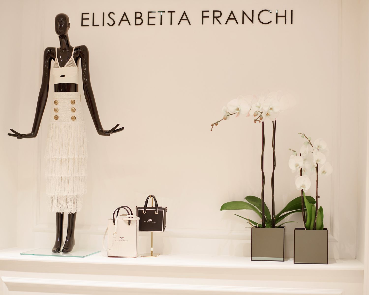 Elisabetta Franchi luxury retail store display with mannequins and white decor.