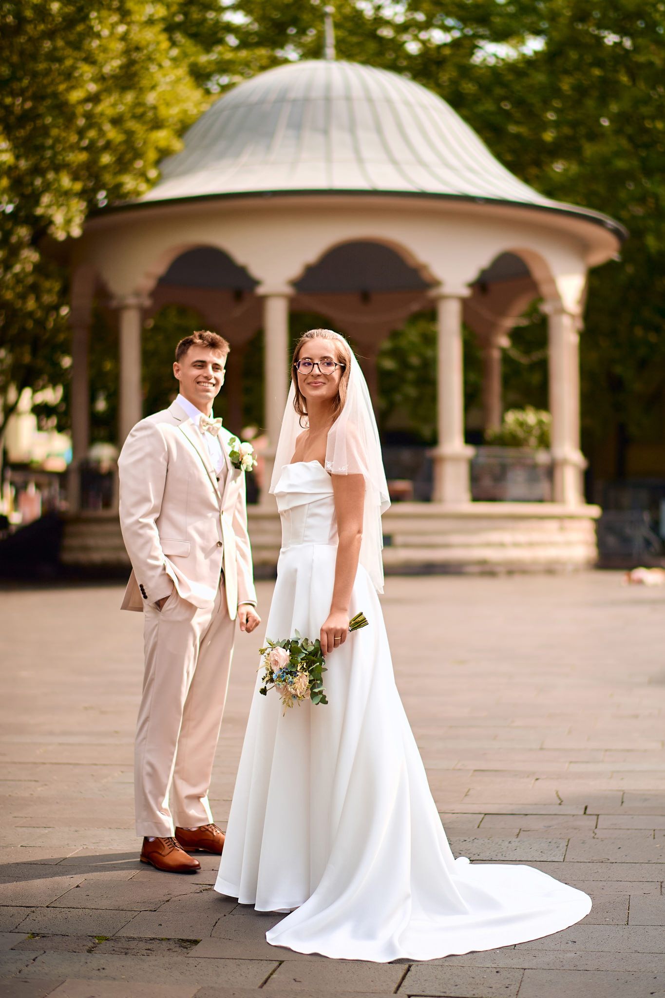 Wedding photos taken in front of ornate white gazebos with beautiful garden scenery.