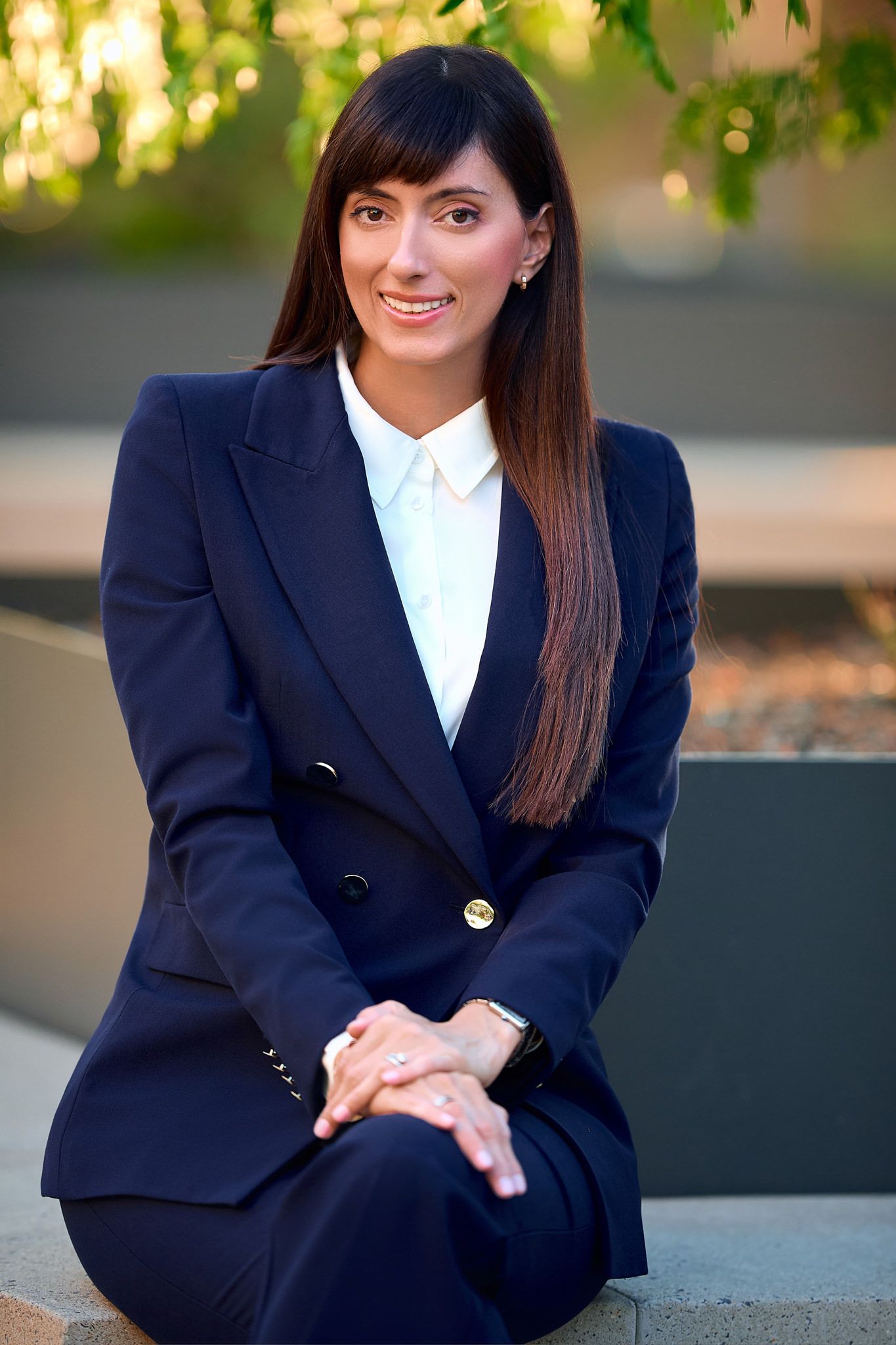 Professional portrait series in a navy blazer against a warm outdoor background.