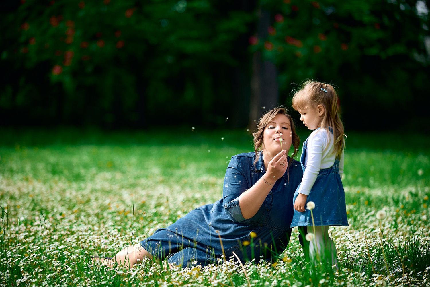 Family relaxing together on grass surrounded by white spring daisies.