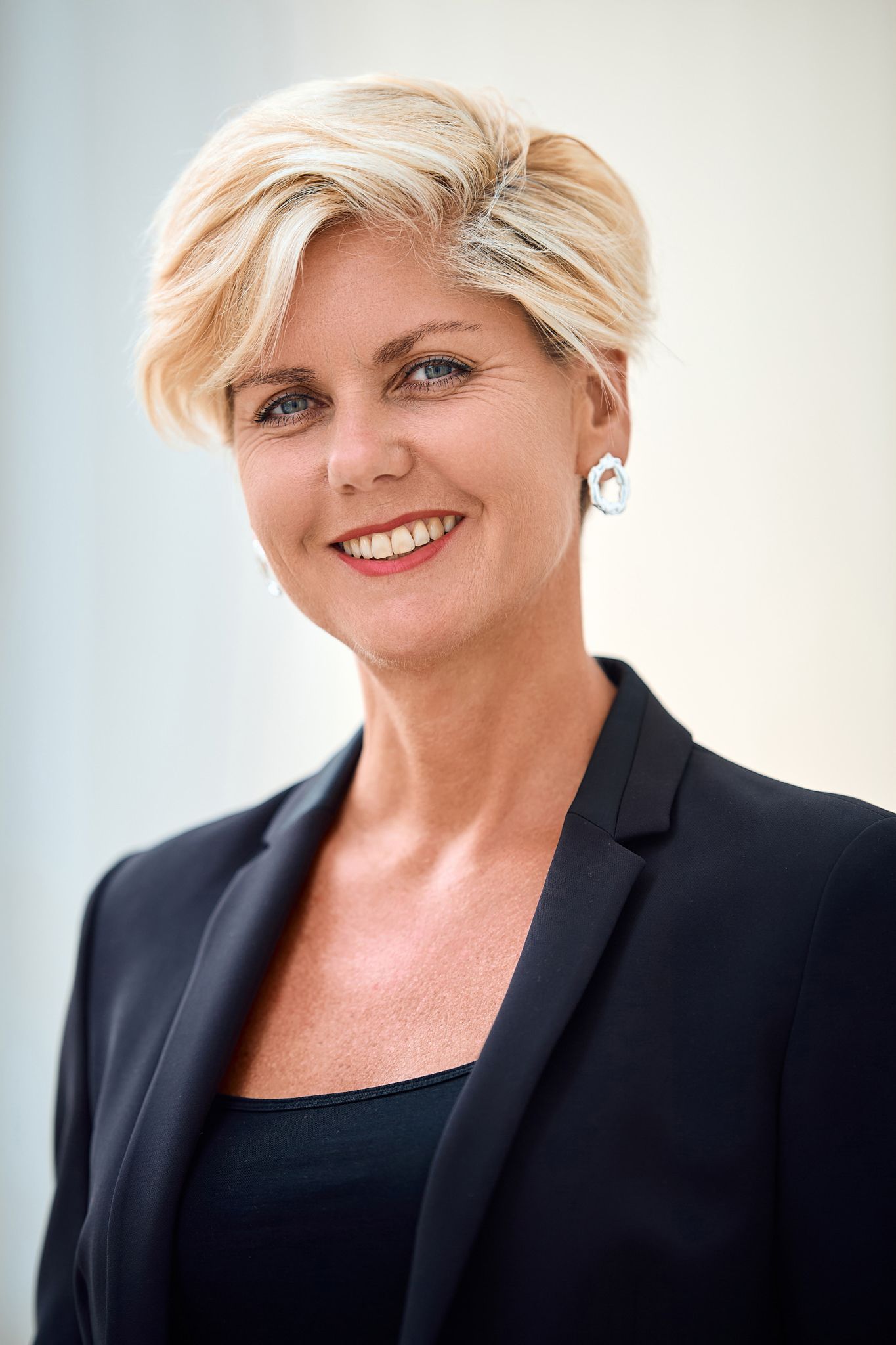 Professional headshot in business attire with short blonde hair.