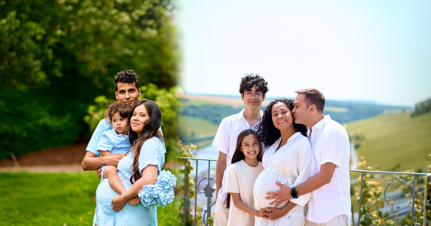 A joyful multigenerational family poses outdoors in a lush green setting, with a pregnant woman centered among loved ones.