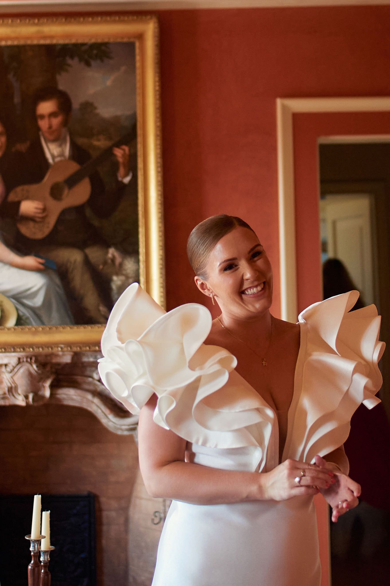 An elegant white ruffled wedding dress detail photographed in a room with red walls.