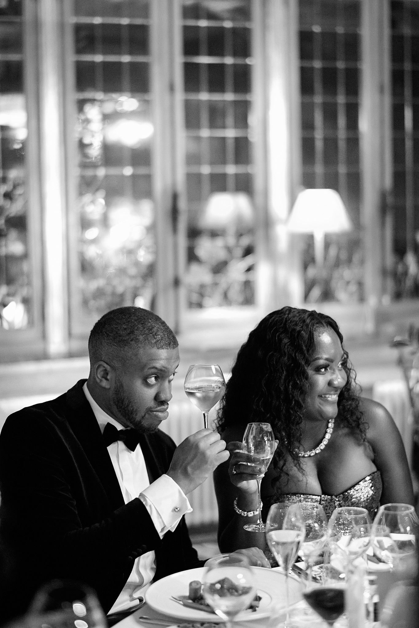 Elegant dinner guests in formal attire enjoy wine and conversation at gala event.