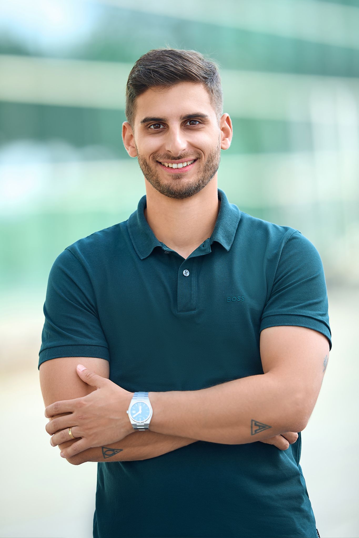 Professional headshots of person in dark polo shirt against blurred background.