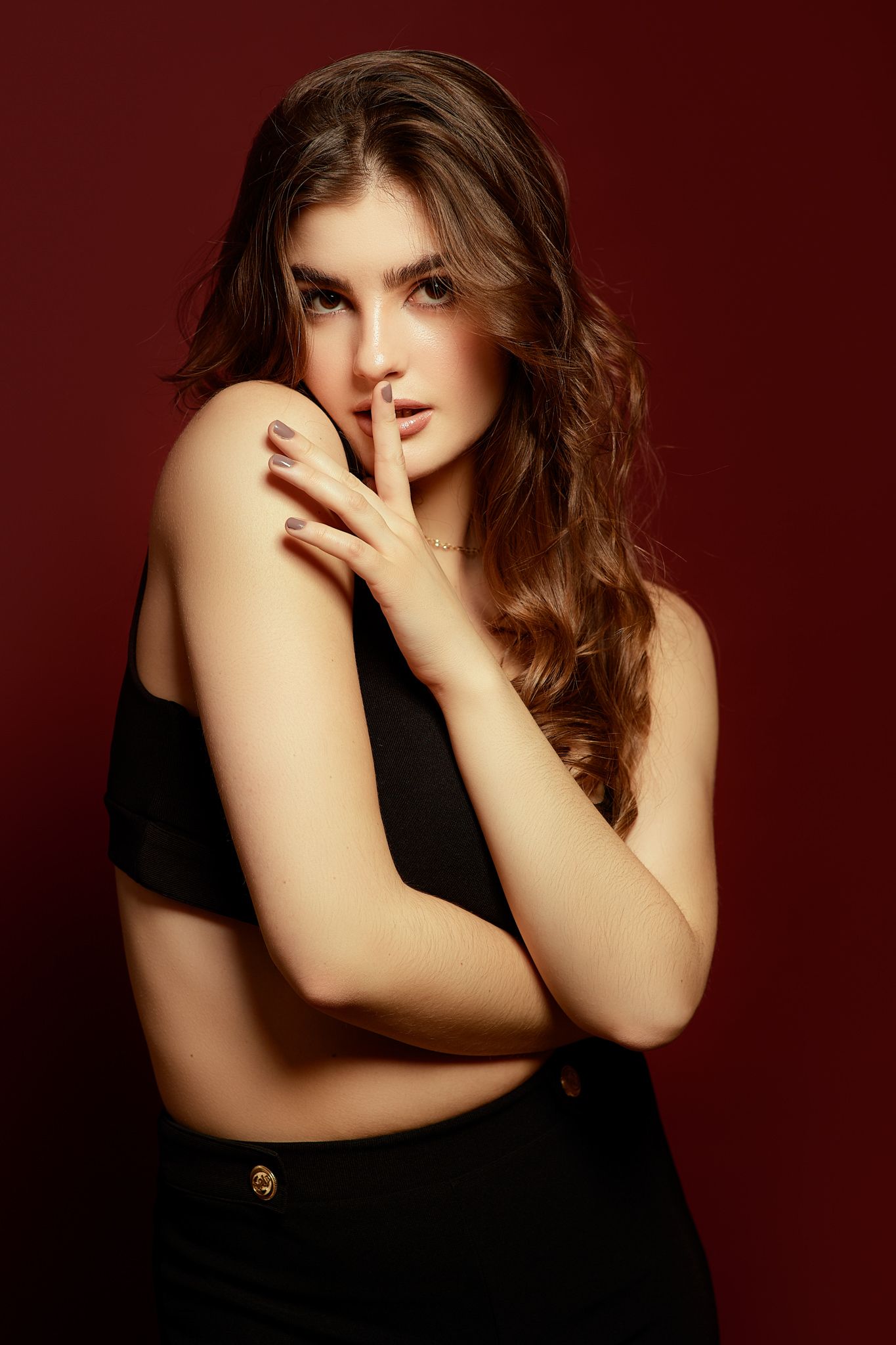 Artistic portrait with natural makeup against deep red background.
