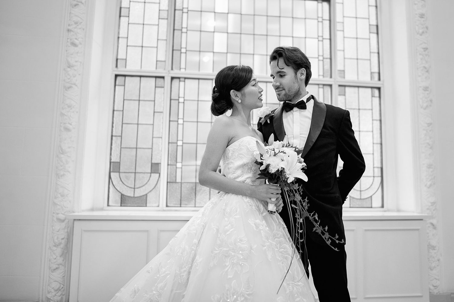 Romantic wedding couple portraits captured in front of elegant church windows.