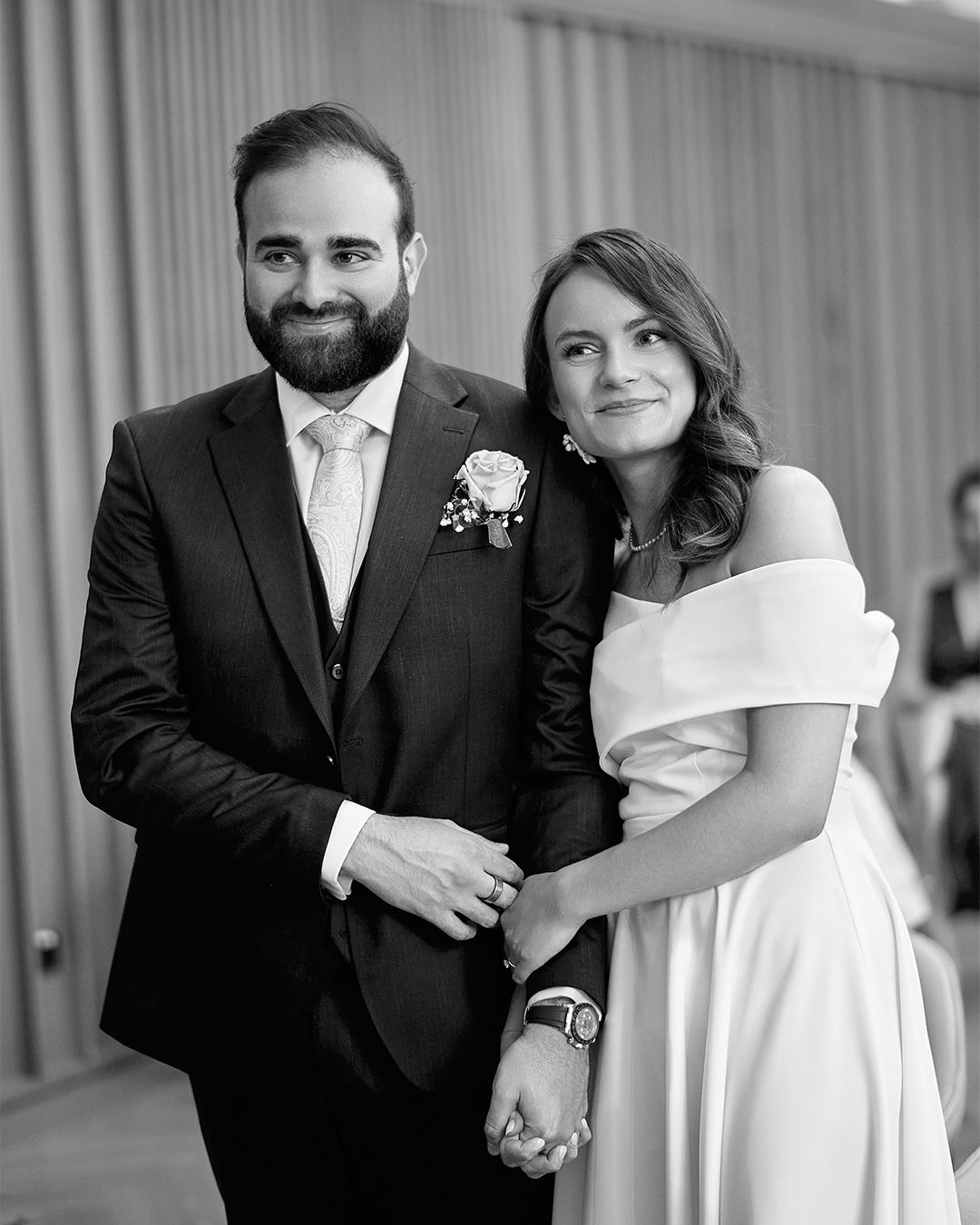 A wedding couple poses together in formal attire for a classic black and white portrait.