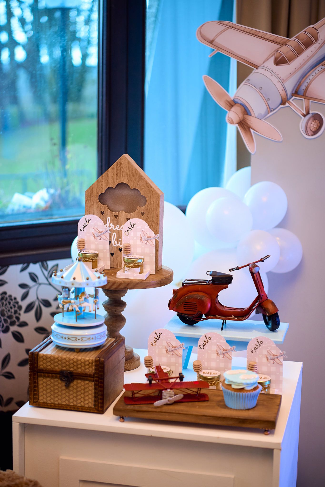 Vintage-themed party decorations featuring toy scooter, birdhouse, and cupcakes on display.