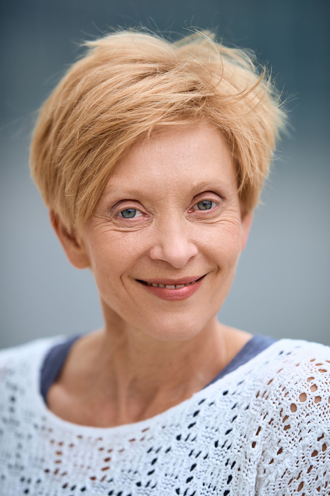 Portrait series showing warm smiles and expressions against blue-gray backdrop.
