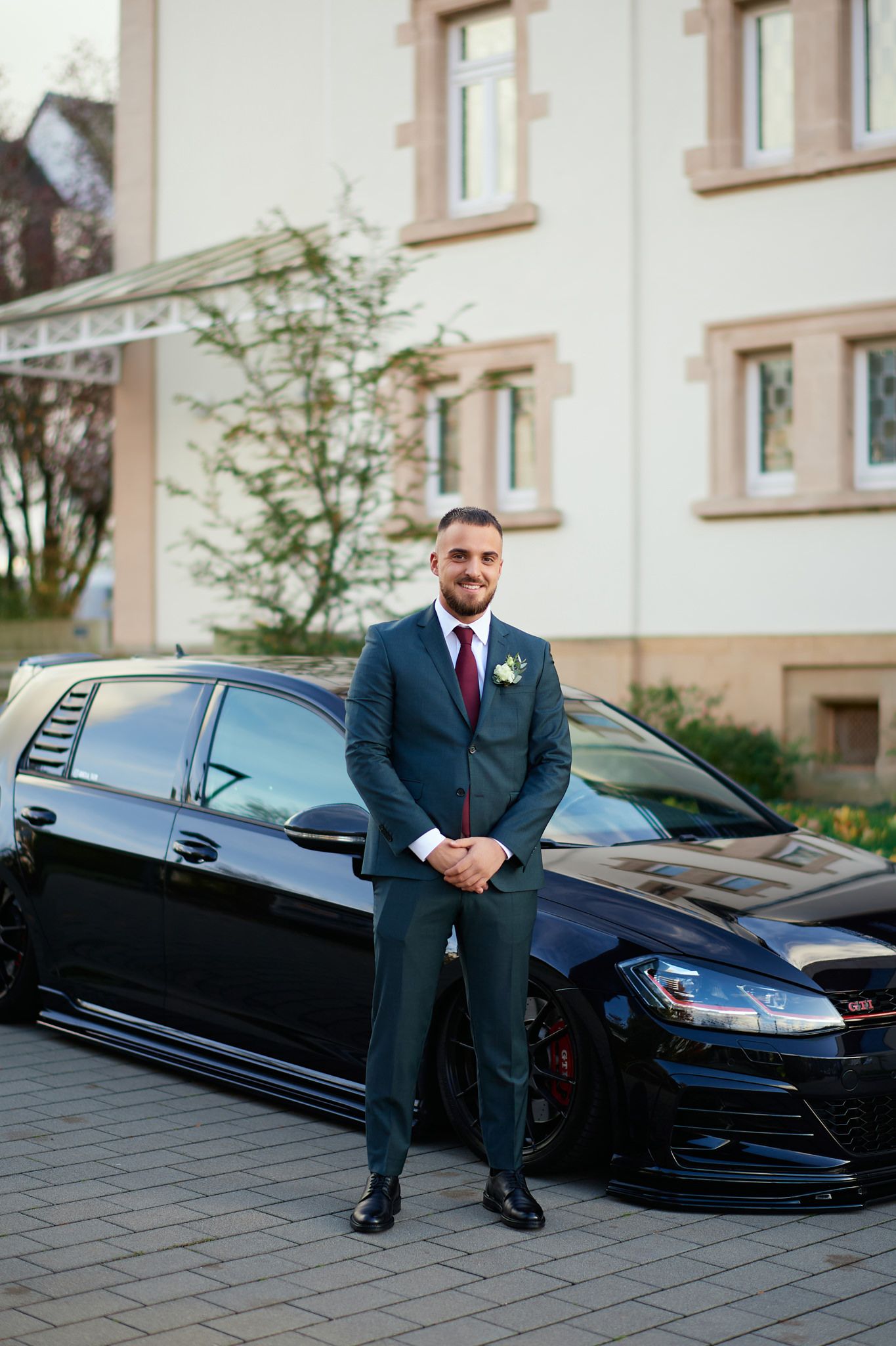 Black luxury limousine parked outside a modern building for a wedding event.