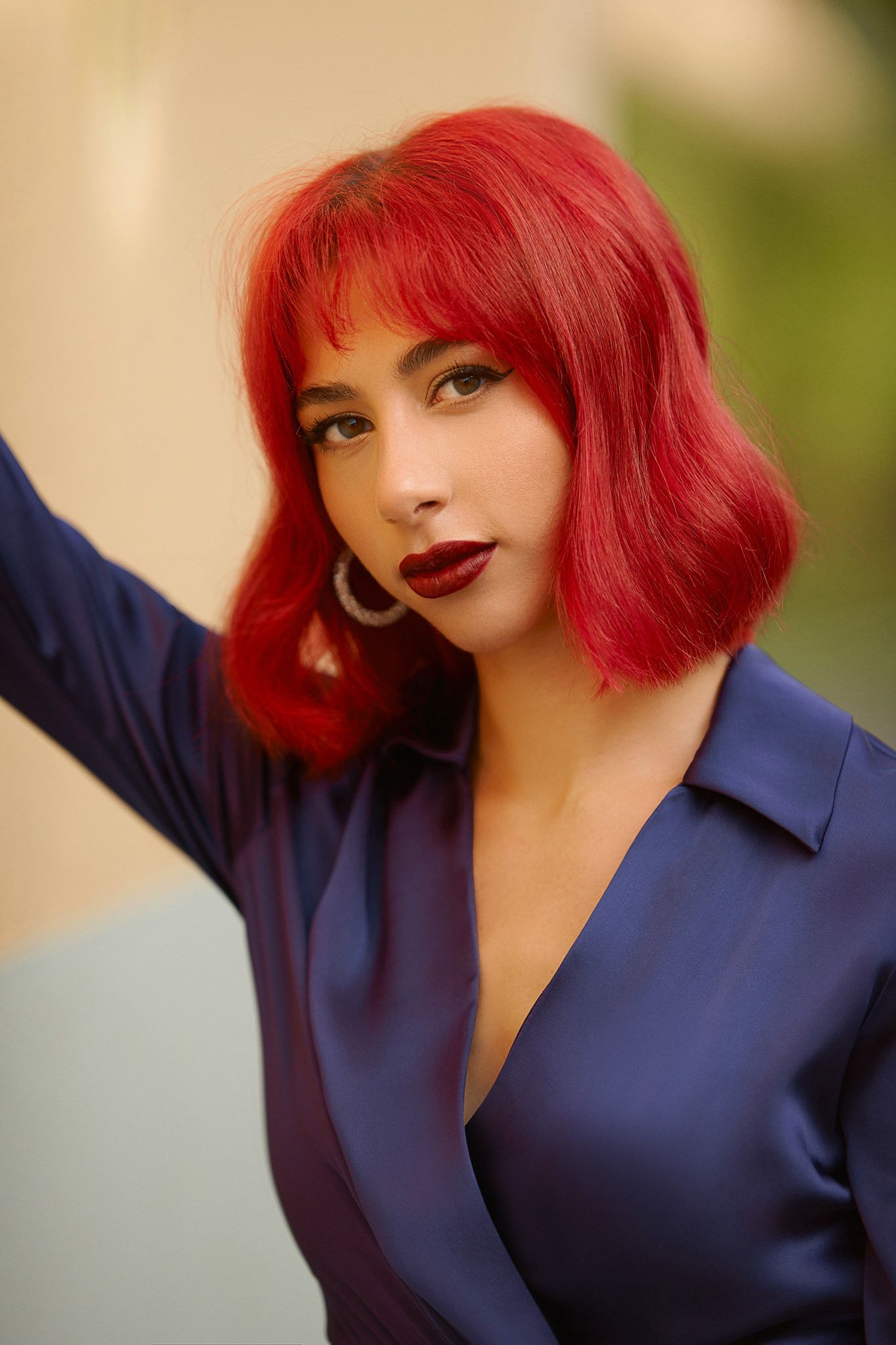 Fashion model with bright red bob haircut poses in navy blue top.