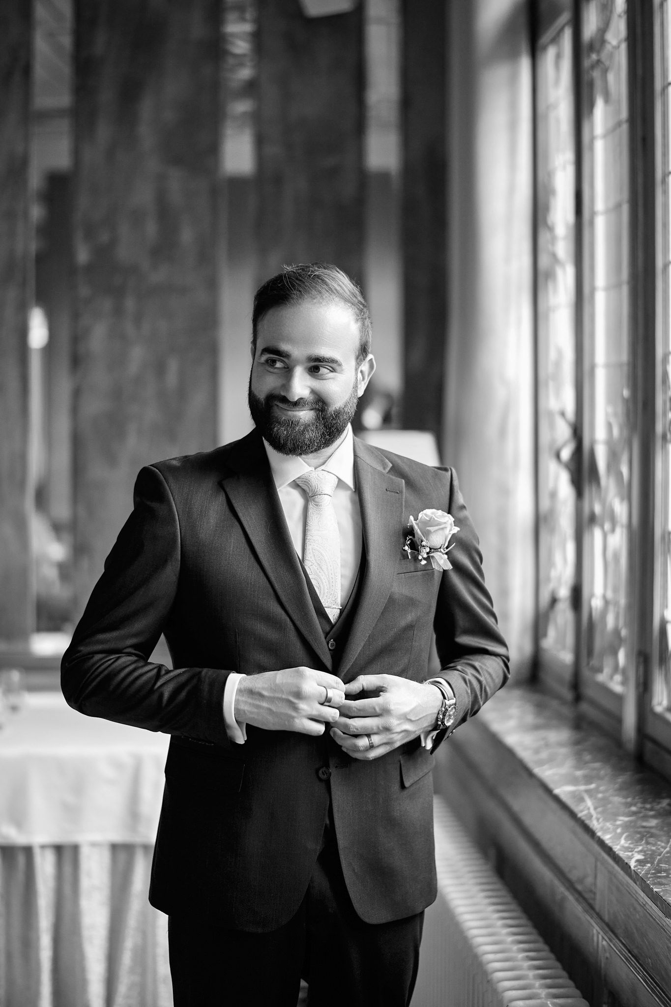 Black and white portraits of a groom in formal attire posing in a hallway.