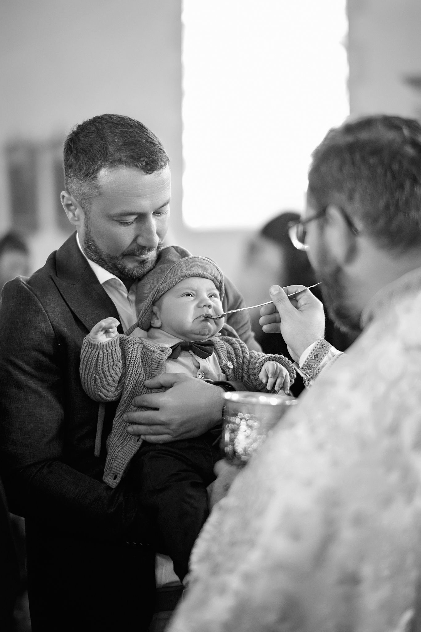 Orthodox baptism ceremony with infant being held during religious ritual in church.